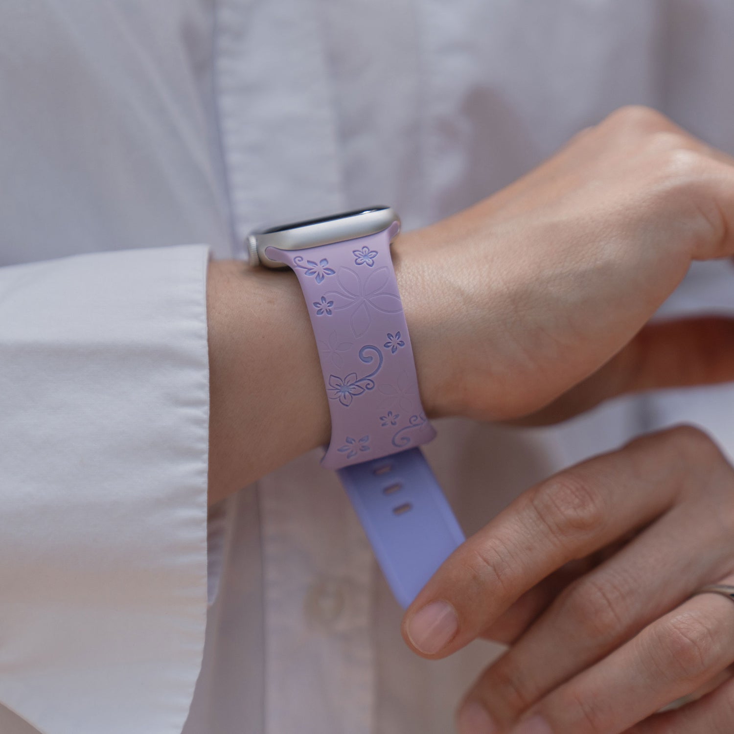 Eine Person trägt das arktisband Apple Watch Silikonarmband "Bloom" mit einem floralen Design am Handgelenk, gepaart mit einem weißen Hemd.