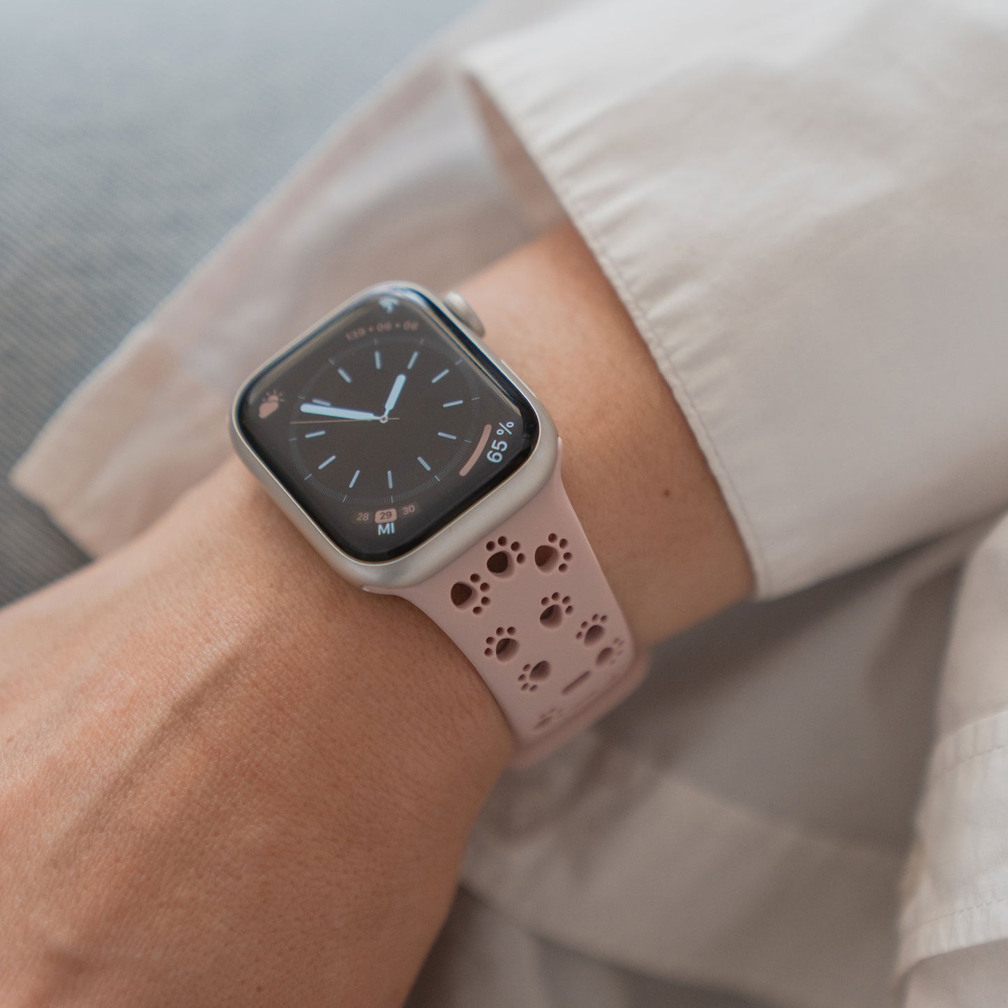 Eine Person in einem weißen langärmeligen Hemd trägt ein arktisband Apple Watch Silikonarmband "Paw" von arktisband mit einem niedlichen Pfotendesign.