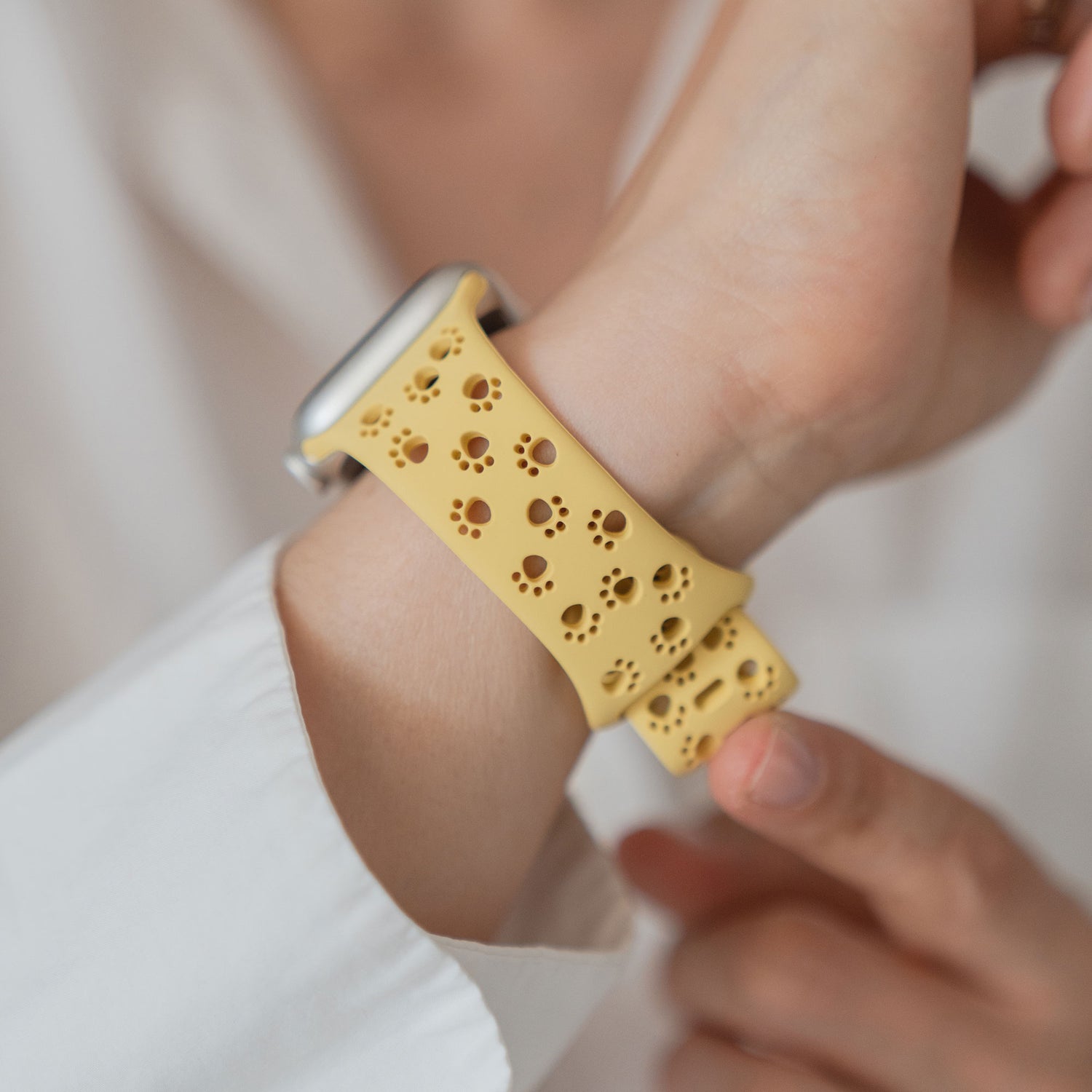Eine Person trägt ein Arktisband Apple Watch Silikonarmband "Paw" mit einem gelben Band mit charmanten Pfotenabdrücken.