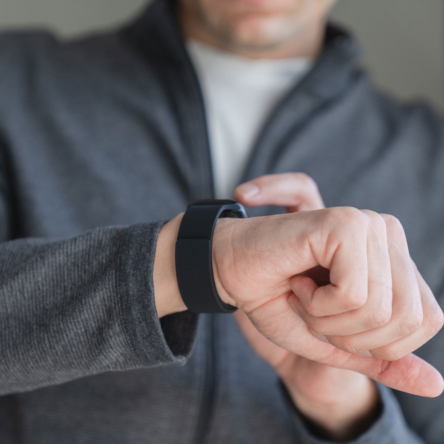 Jemand trägt ein Arktisband Apple Watch magnetisches Silikonarmband "Flexy" mit Magnetverschluss am Handgelenk und interagiert damit, bekleidet mit einer grauen Jacke.