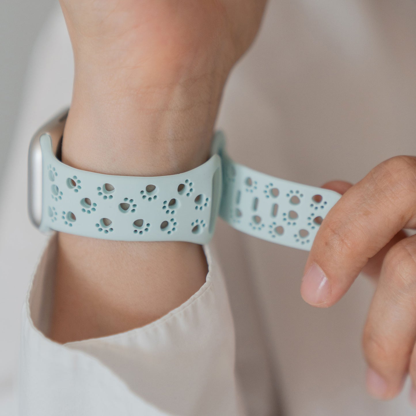 Jemand befestigt das Arktisband Apple Watch Silikonarmband "Paw", ein weißes Arktisband mit kleinen Pfotenausschnitten im Pfoten Design.