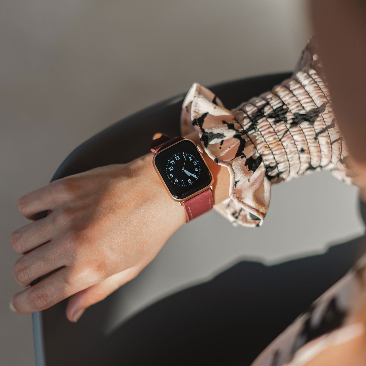 Jemand, der das arktisband Apple Watch Lederarmband "Premium" in Braun trägt, gepaart mit einem gemusterten langärmeligen Oberteil, stützt seinen Arm auf einen Stuhl.