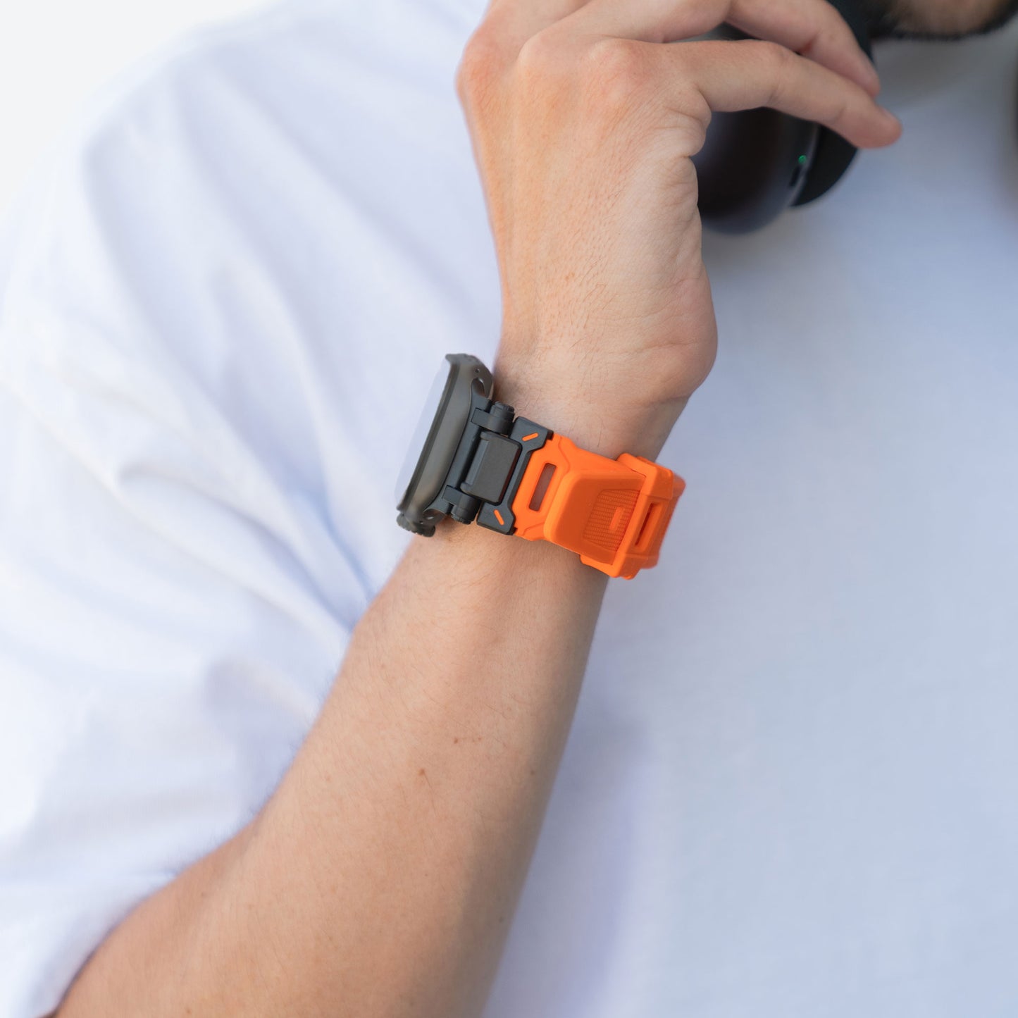 Eine Person im weißen Hemd hält ein Telefon ans Ohr und präsentiert das arktisband Apple Watch Ultra Armband „Atlas“ von arktisband an ihrem linken Handgelenk, wobei der Fokus auf diesem auffälligen Accessoire liegt.
