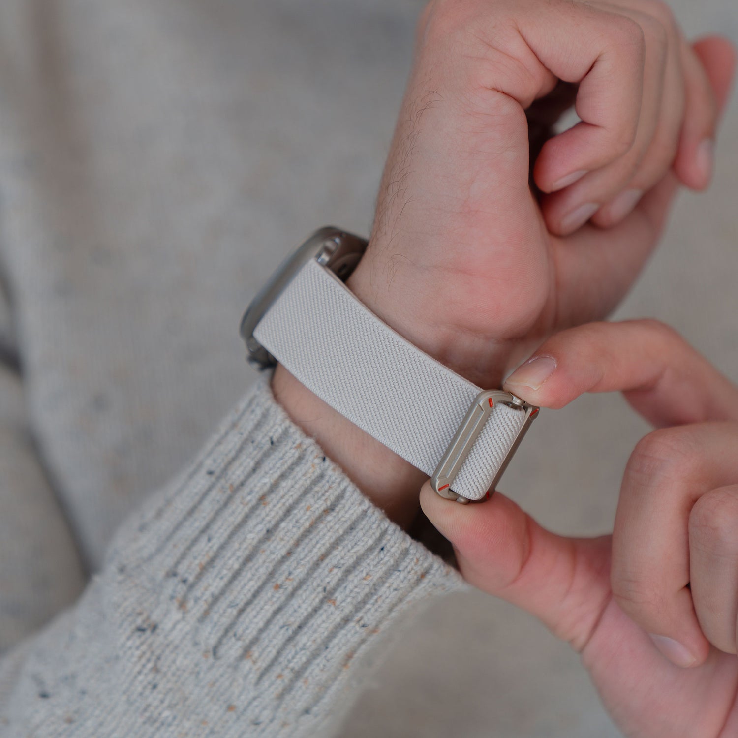 Jemand passt das Arktisband Apple Watch Nylonarmband "FlexOne" in weiß an sein Handgelenk an.