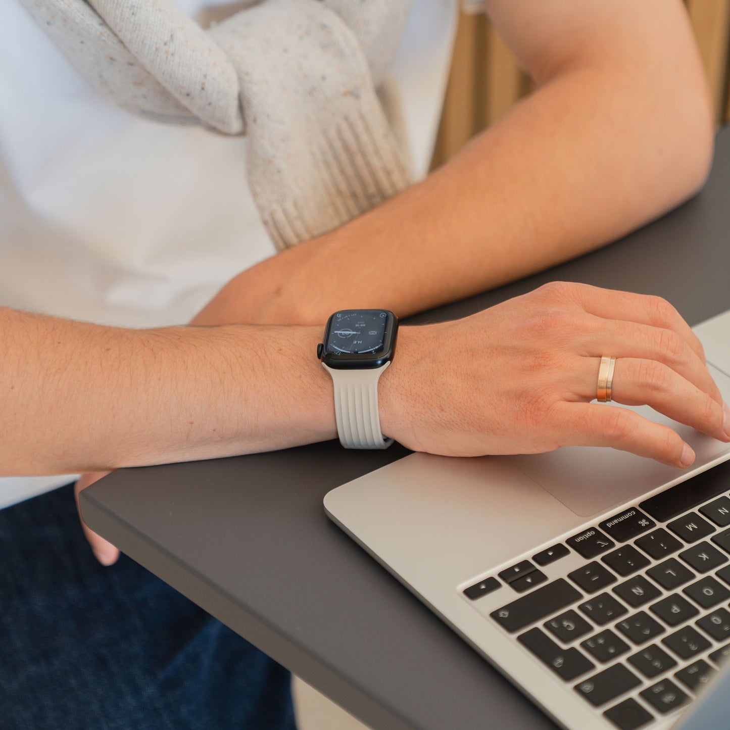 Eine Person, die ein arktisband Apple Watch Armband "Skandi" von arktisband trägt, benutzt einen Laptop, wobei ein Ehering an der linken Hand sichtbar ist.