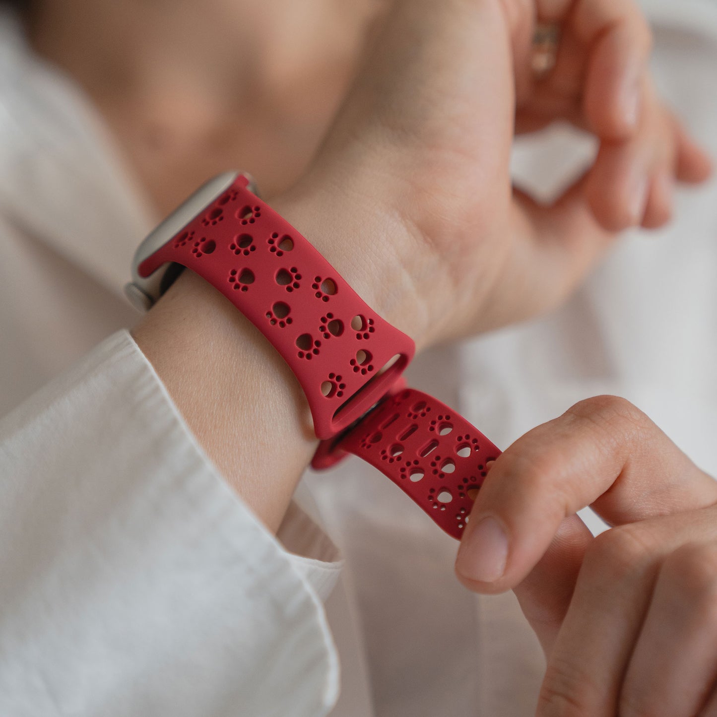 Nahaufnahme einer Person, die das Arktisband Apple Watch Silikonarmband "Paw" mit rotem Band und stilvollen Ausschnitten im Pfotendesign trägt.