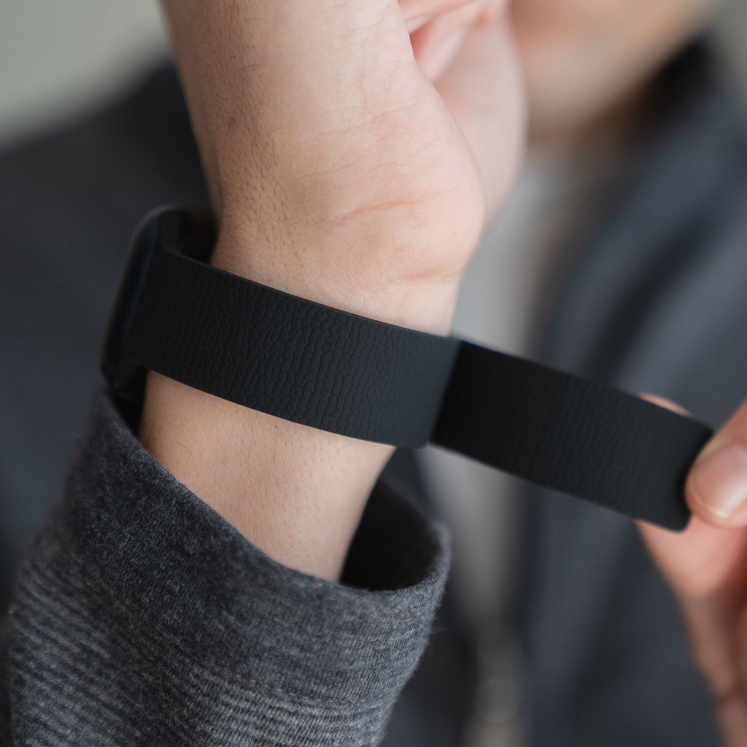 Jemand, der ein Arktisband Apple Watch trägt, magnetisiert das Silikonarmband "Flexy" in Schwarz an seinem Handgelenk.