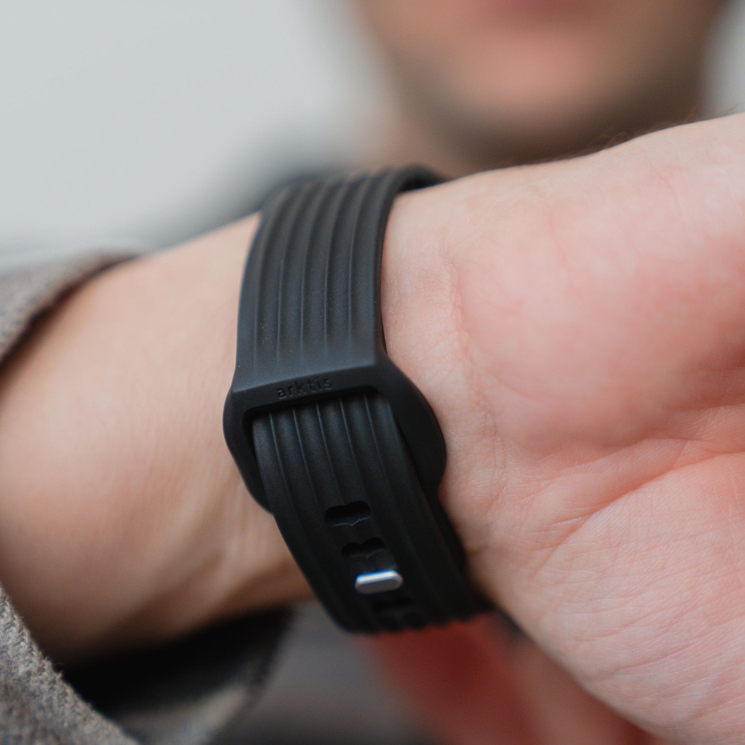 Nahaufnahme eines Handgelenks, das das arktisband Apple Watch Armband "Skandi" trägt - ein schwarzes, geripptes Fluorelastomer-Sportarmband mit Kunststoffschließe von arktisband im klassischen Skandi-Design.