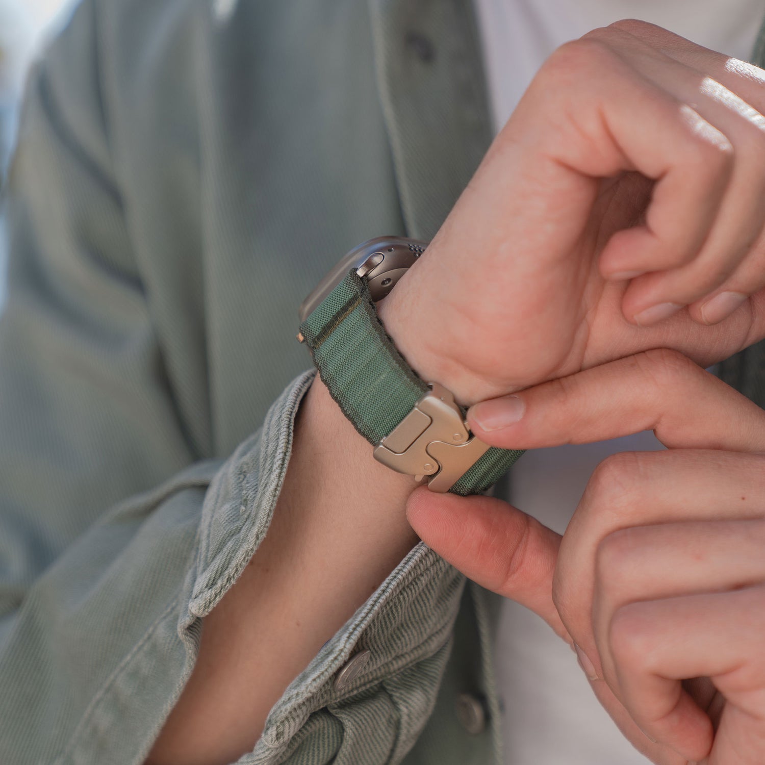 Eine Person, die das arktisband Apple Watch Armband "CoreX" in Grün trägt, stellt ihre Armbanduhr mit der anderen Hand ein.