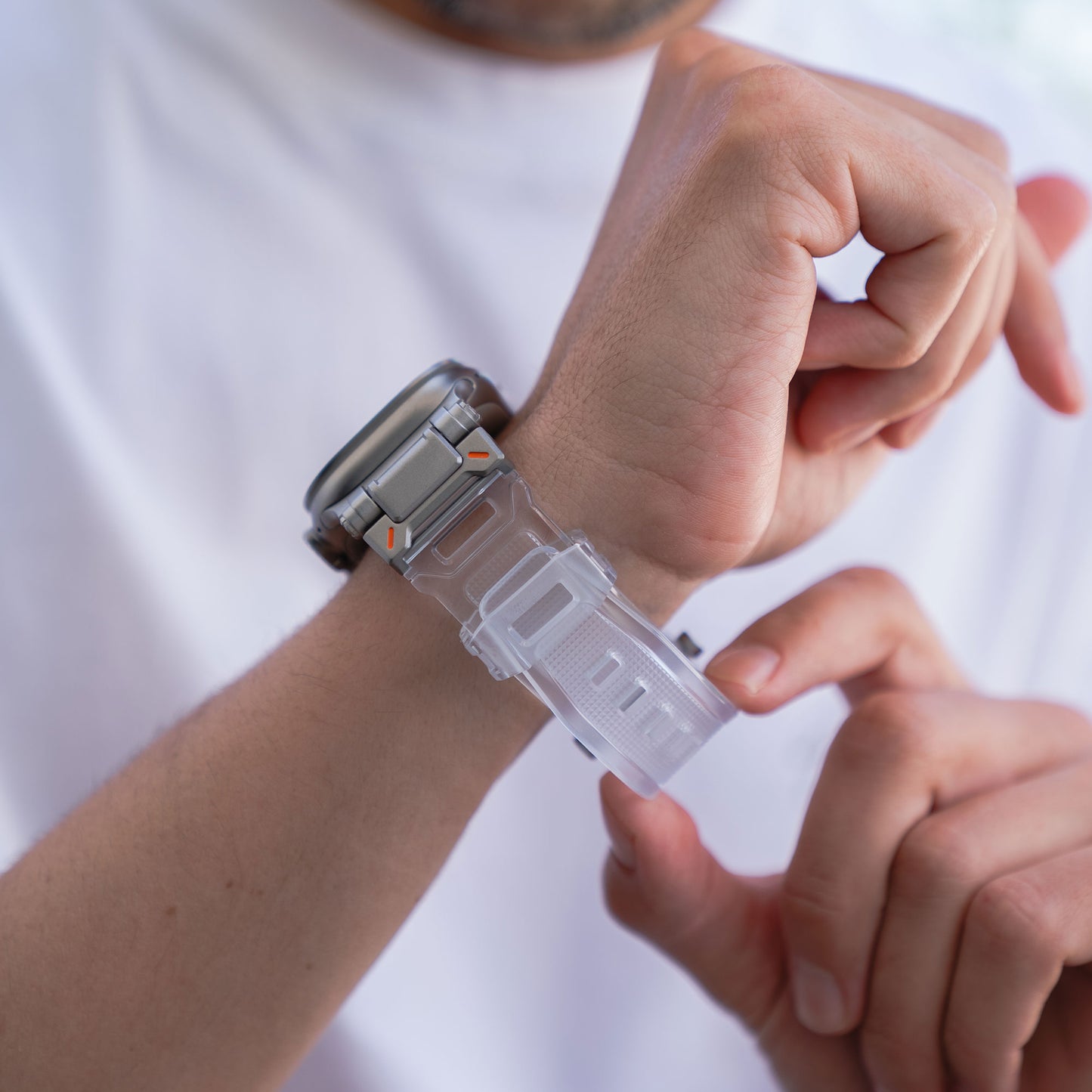 Eine Person befestigt ein Arktisband Apple Watch Ultra Armband „Atlas“ am Handgelenk und kombiniert es mit einem frischen weißen Hemd.