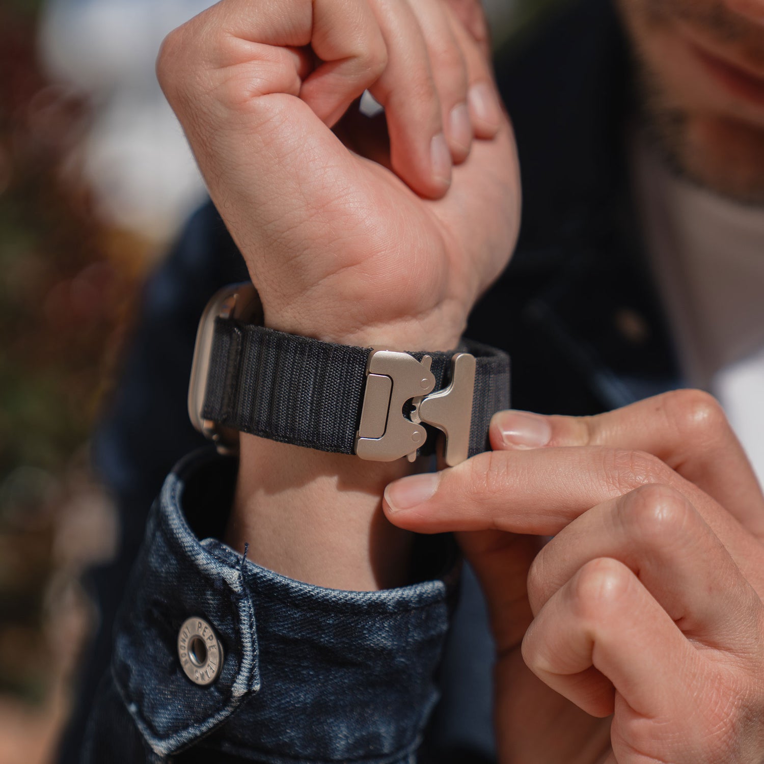 Nahaufnahme einer Person, die das arktisband Apple Watch Armband "CoreX" mit einem Parachute-Verschluss an ihrem Handgelenk befestigt.