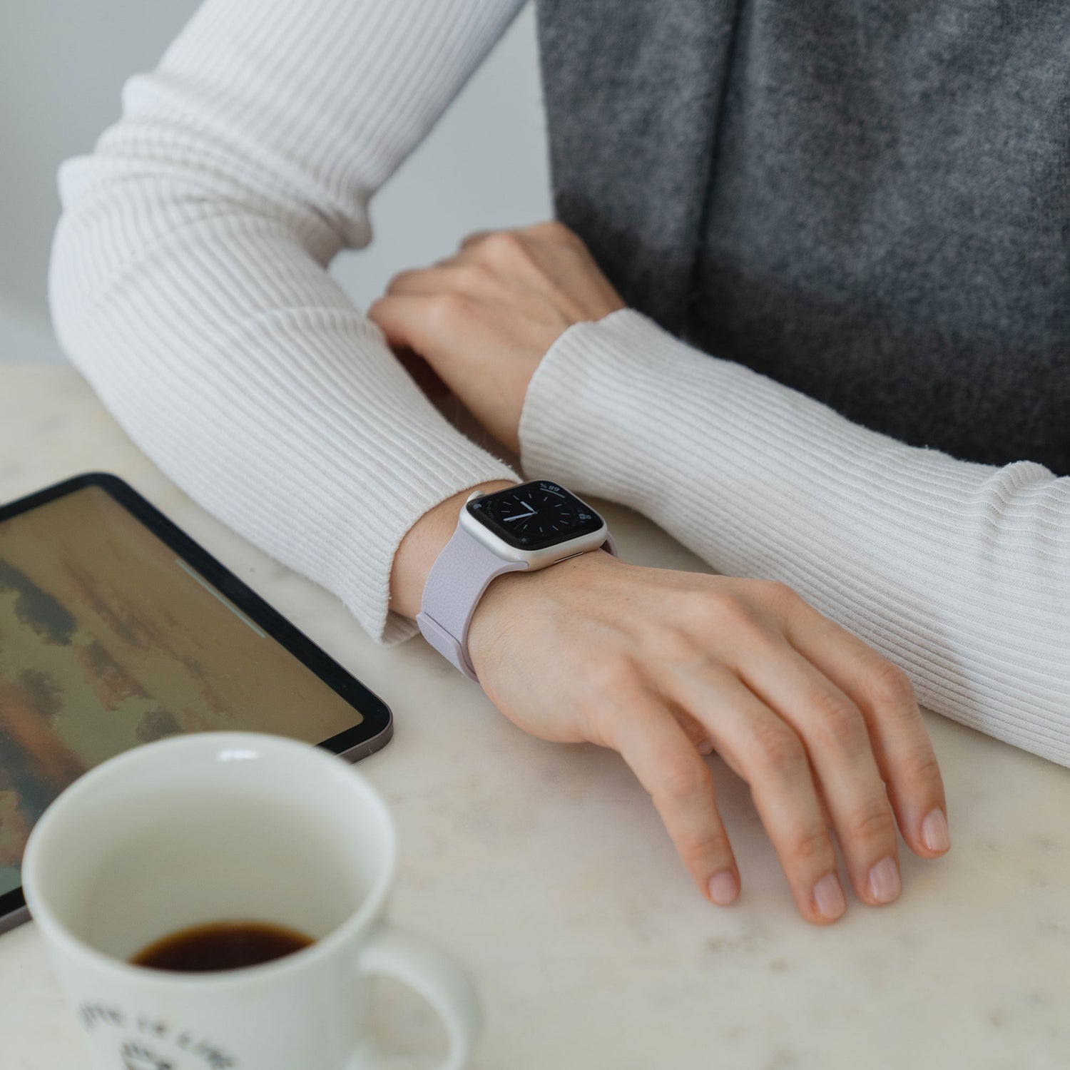 Jemand, der eine arktisband Apple Watch magnetisches Silikonarmband "Flexy" von arktisband trägt, stützt seinen Arm auf einen Tisch neben einem Tablet und einer Tasse Kaffee.