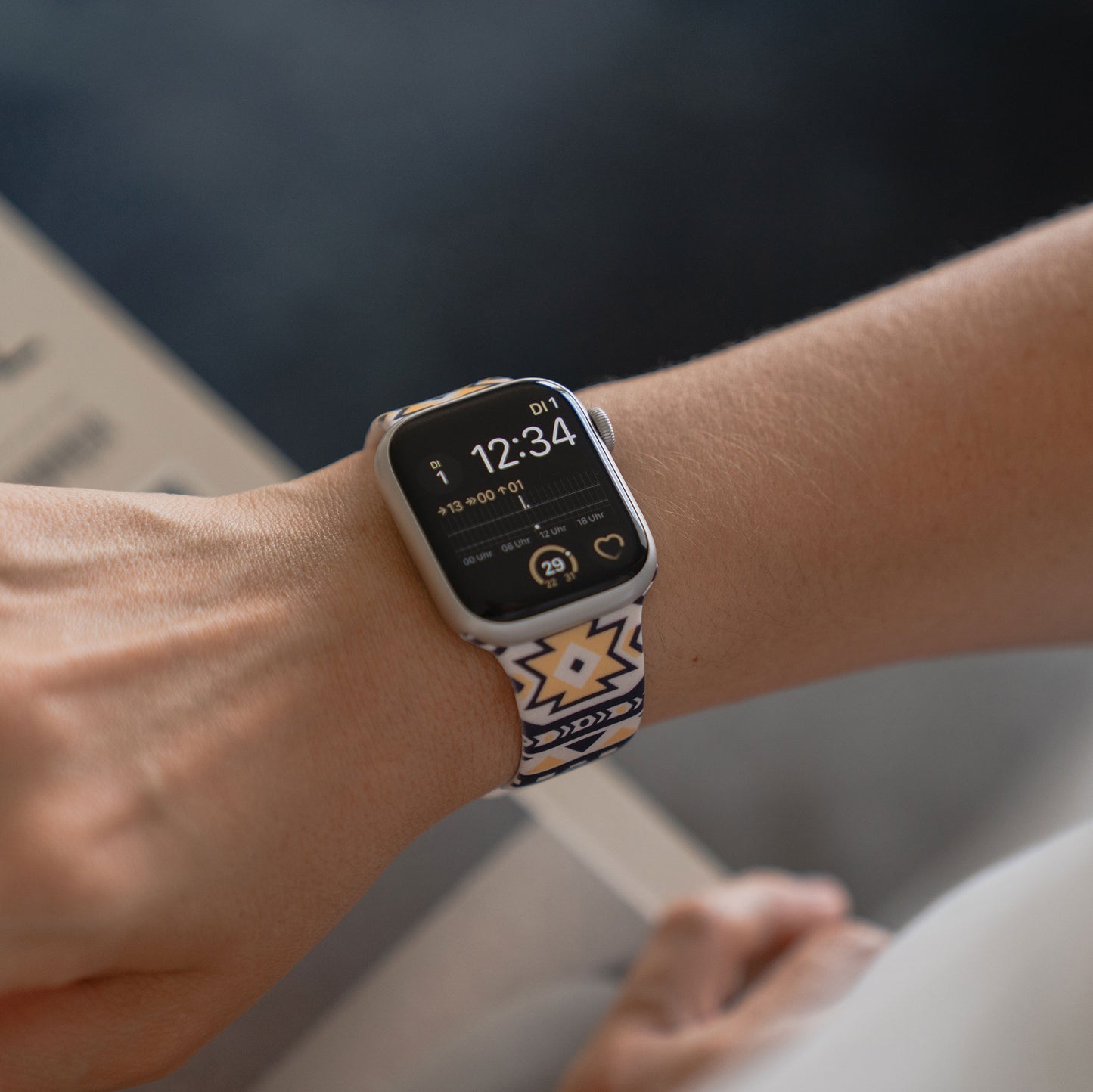 Eine Person trägt ein arktisband Aztec Apple Watch Armband von arktisband mit einem stilvollen Silikonarmband, das die Uhrzeit 12:34 anzeigt - ideal für einen aktiven Lebensstil.