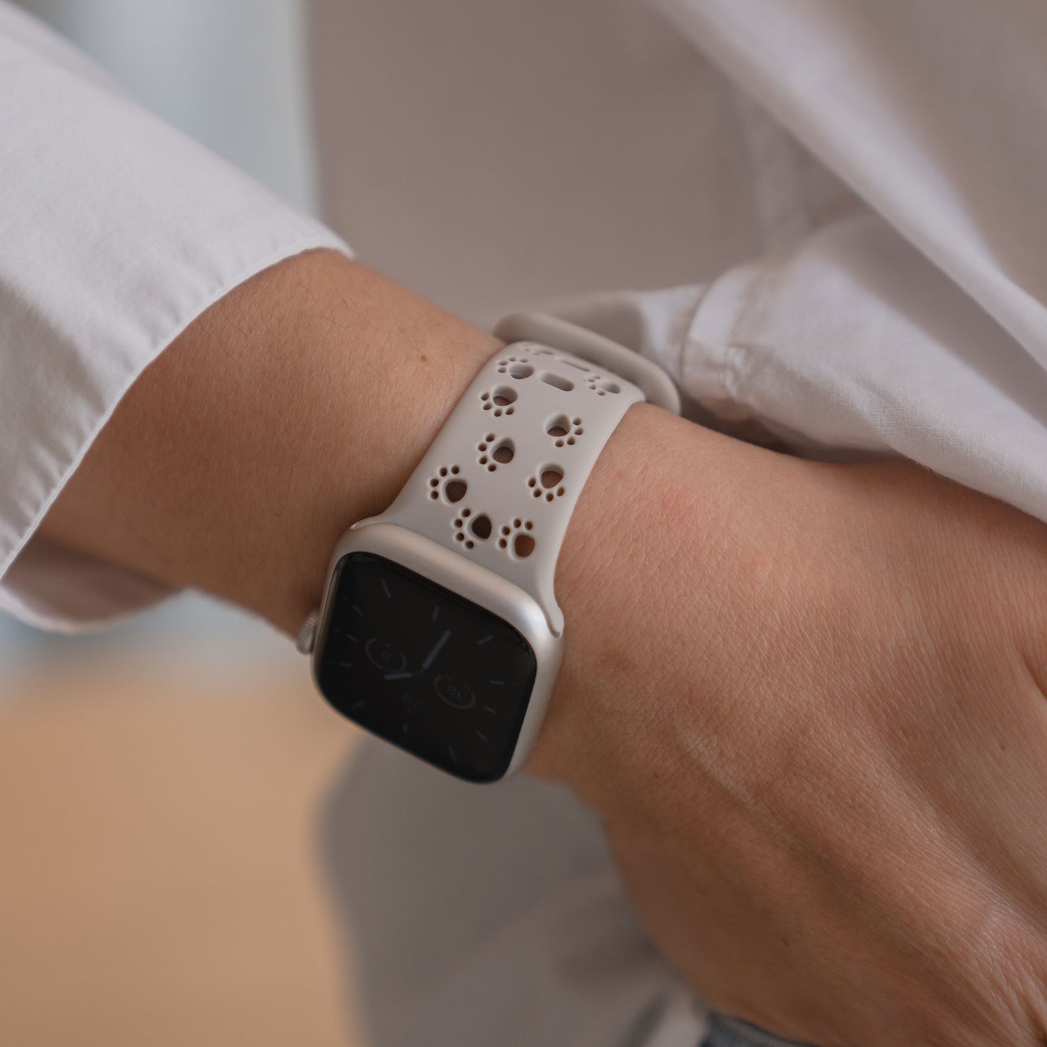 Eine Person trägt ein Arktisband Apple Watch Silikonarmband "Paw" mit einem weißen Band mit Pfotenabdrücken, die Hand in der Tasche.