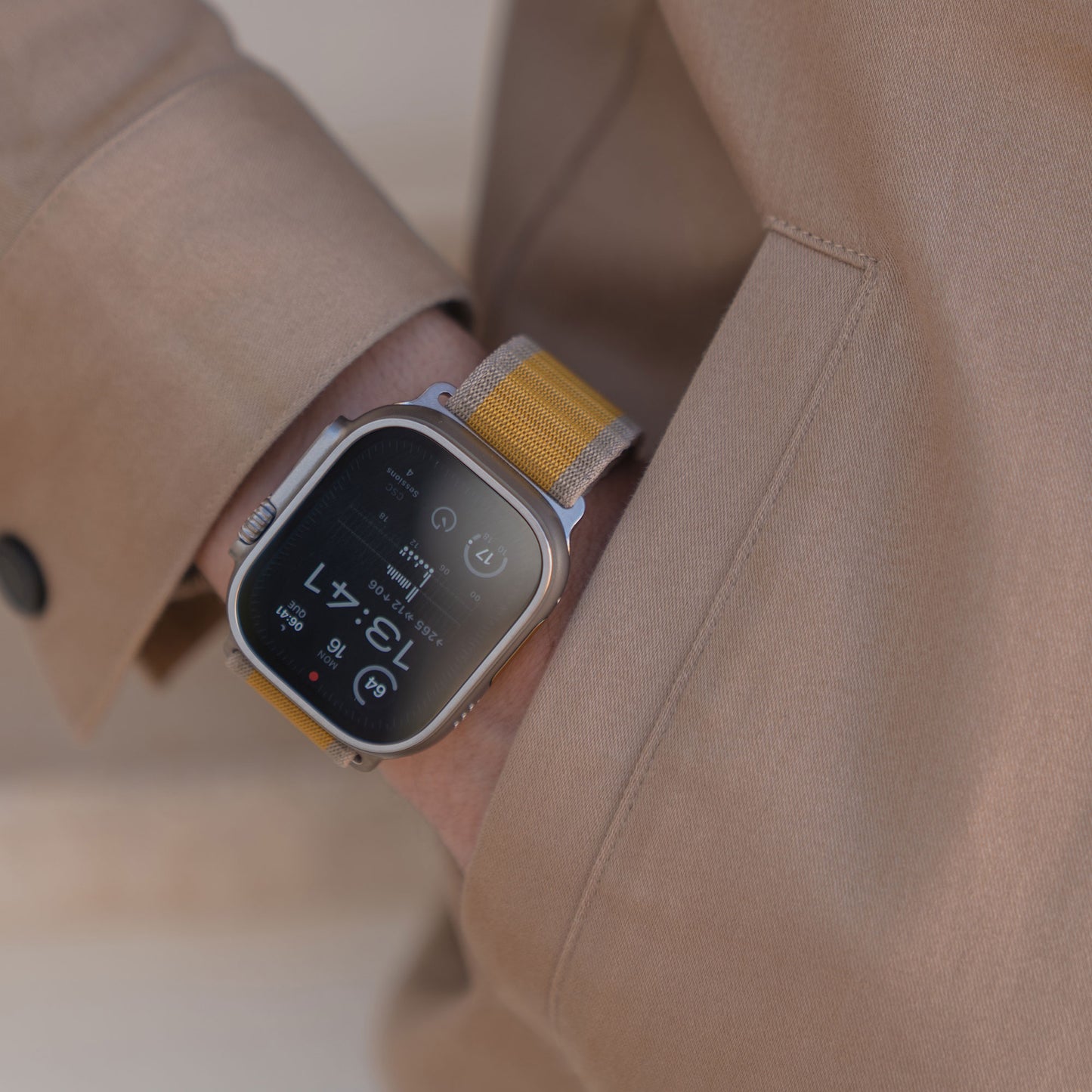 Eine Person im hellbraunen Mantel trägt ein arktisband Apple Watch Armband "CoreX" mit gelbem Armband und Fallschirm-Verschluss, die Hand in der Tasche versteckt.
