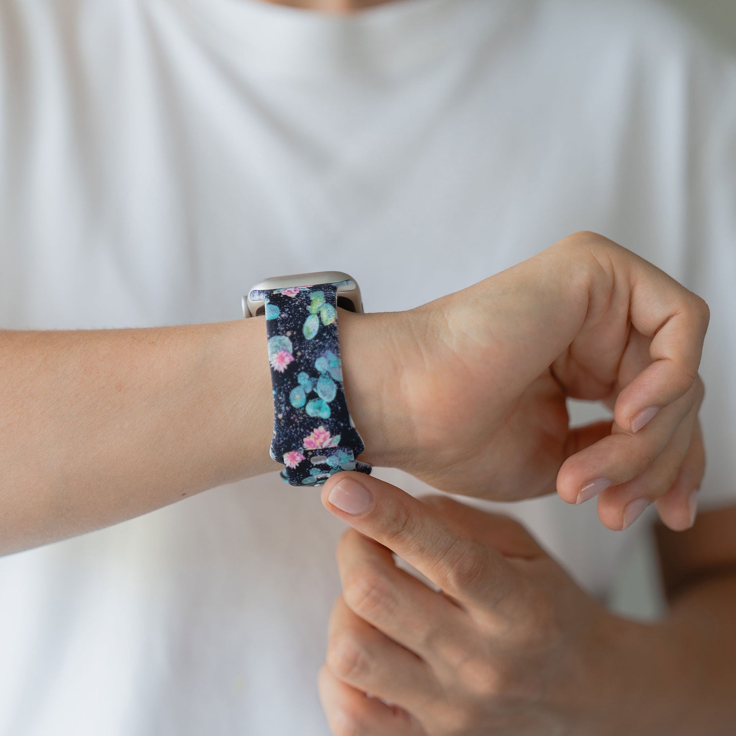Eine Person, die ein arktisband Desert Apple Watch Armband von arktisband mit einem floralen Silikonarmband trägt, berührt den Bildschirm mit ihrem Finger, bereit für sportliche Aktivitäten.