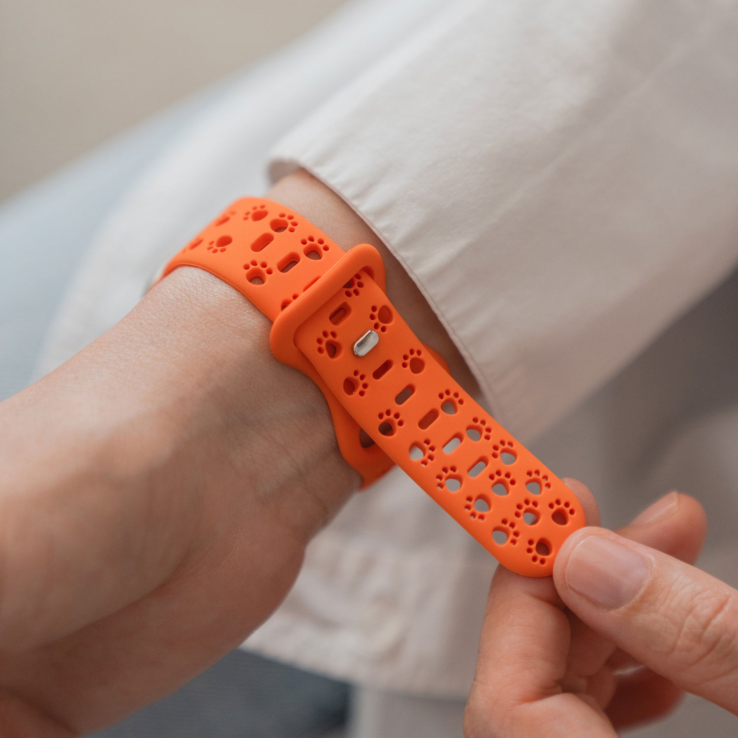 Eine Person befestigt ein arktisband Apple Watch Silikonarmband "Paw" von arktisband mit Löchern in Form von Pfotenabdrücken an ihrem Handgelenk.