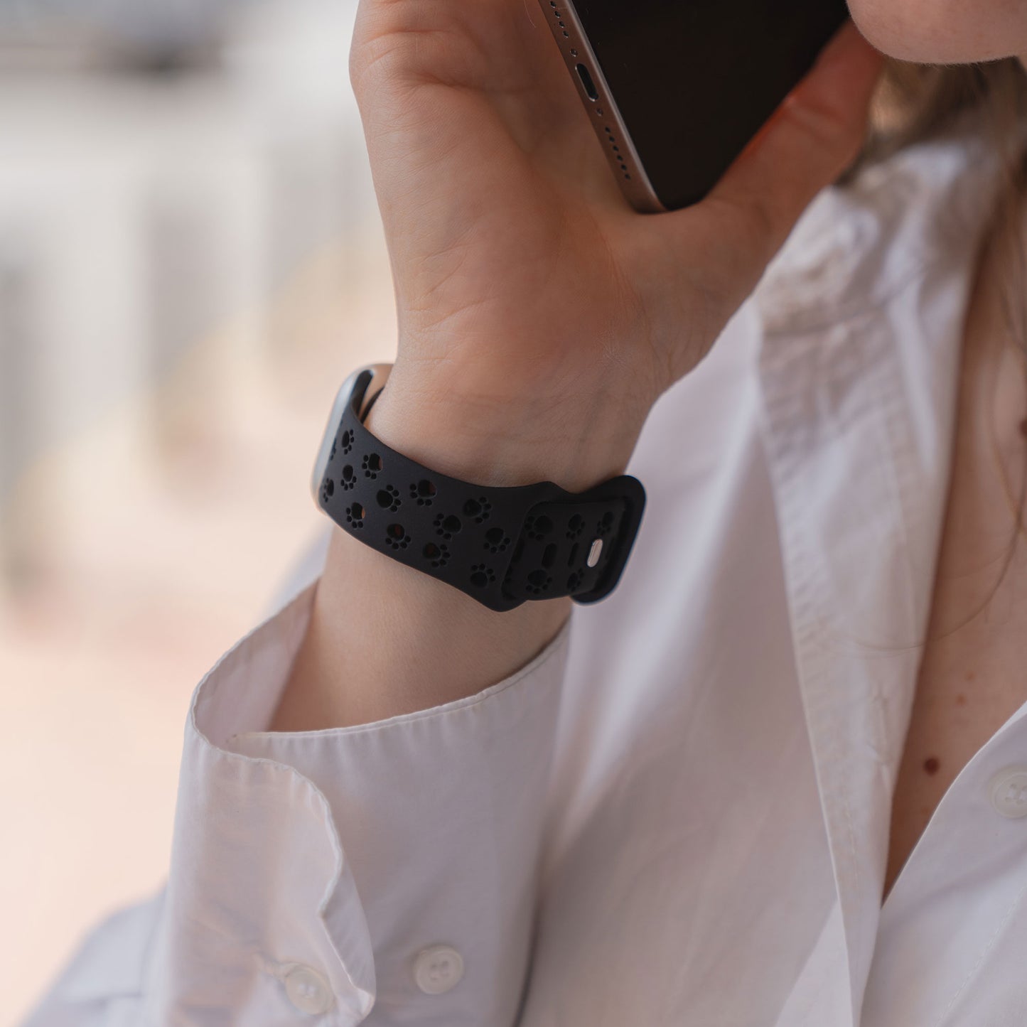 Person mit weißem Hemd und einem arktisband Apple Watch Silikonarmband "Paw" von arktisband, die sich ein Telefon ans Ohr hält.