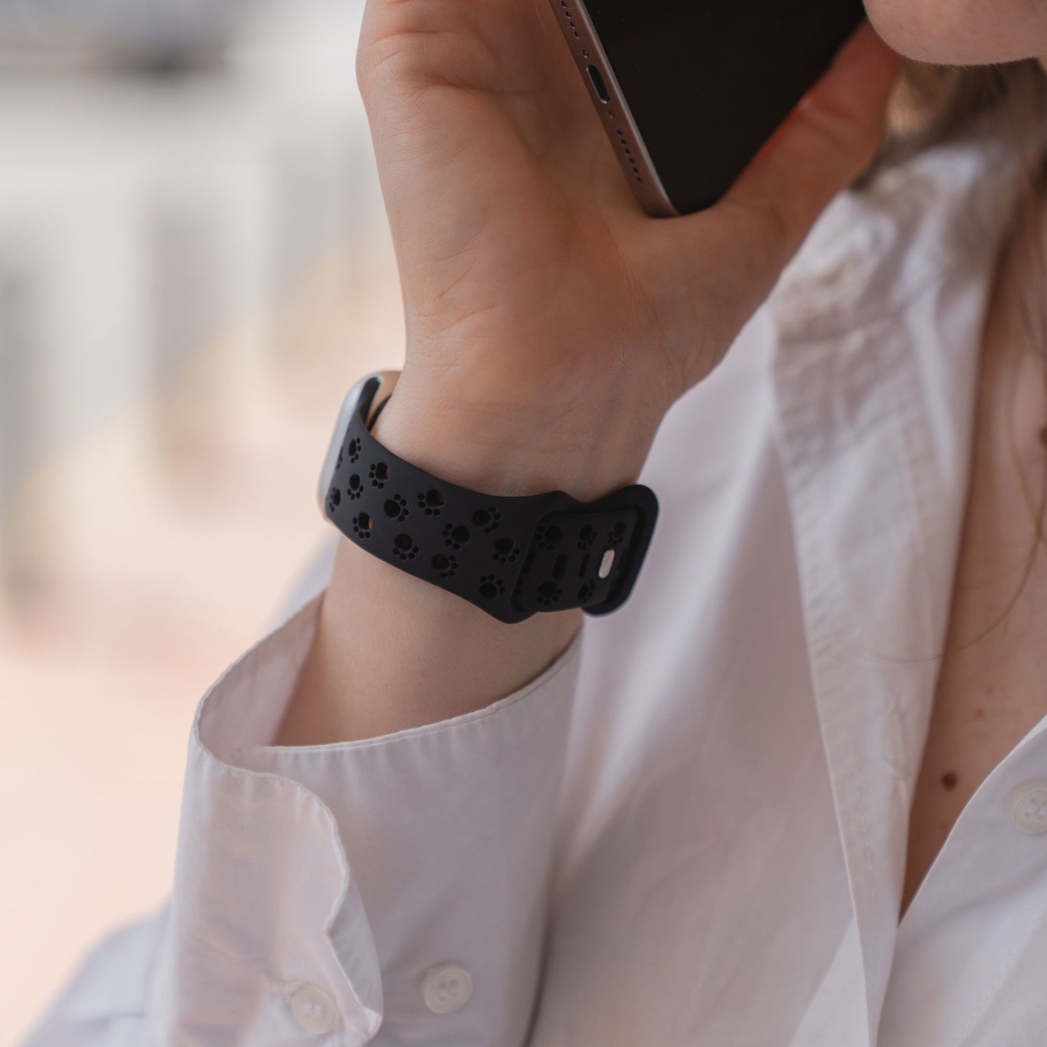 Person mit weißem Hemd und einem arktisband Apple Watch Silikonarmband "Paw" von arktisband, die sich ein Telefon ans Ohr hält.
