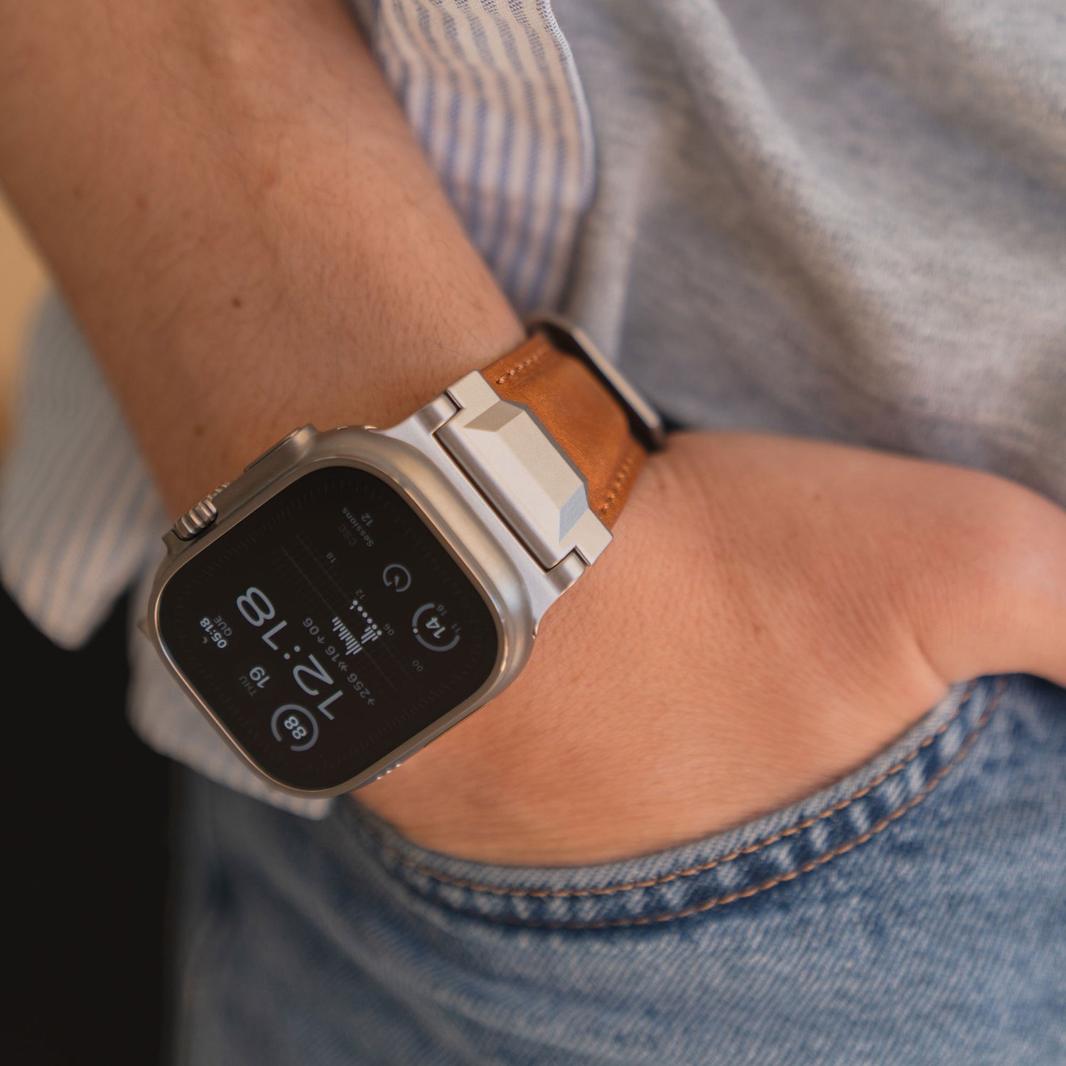 Nahaufnahme einer Person, die ein Arktisband Apple Watch Ultra Lederarmband "Delta" mit Edelstahlschnalle trägt, die Hand lässig in die Jeanstasche gesteckt.