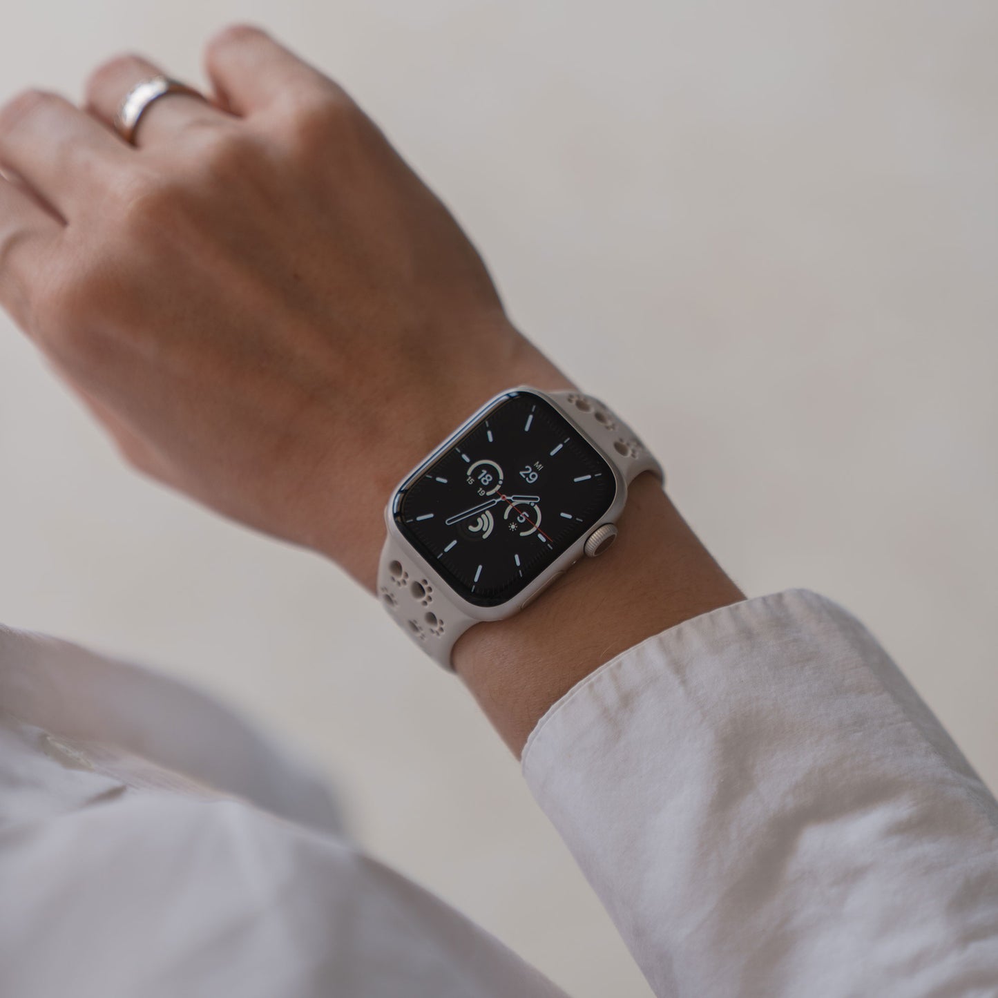 Eine Person trägt ein Arktisband Apple Watch Silikonarmband "Paw" in Weiß, das ein digitales Ziffernblatt anzeigt.