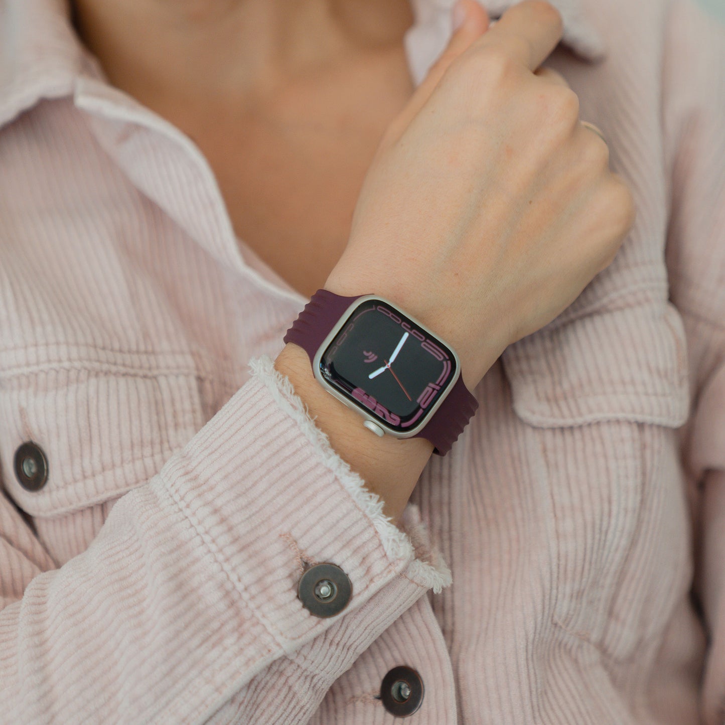 Nahaufnahme einer Person, die ein arktisband Apple Watch Armband "Skandi" in Lila und ein hellrosa Cordhemd trägt.