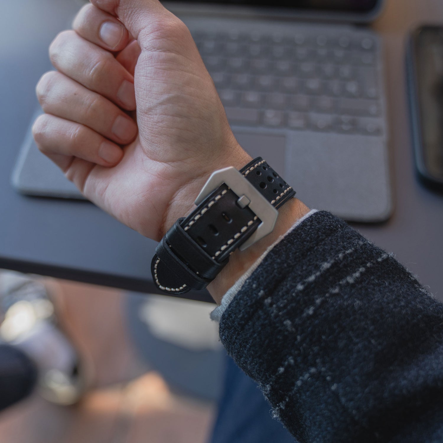 Eine Person trägt ein arktisband Apple Watch Lederarmband "Toronto" aus Echtleder im Vintage-Design mit weißer Naht am Handgelenk, nahe einer Laptop-Tastatur.
