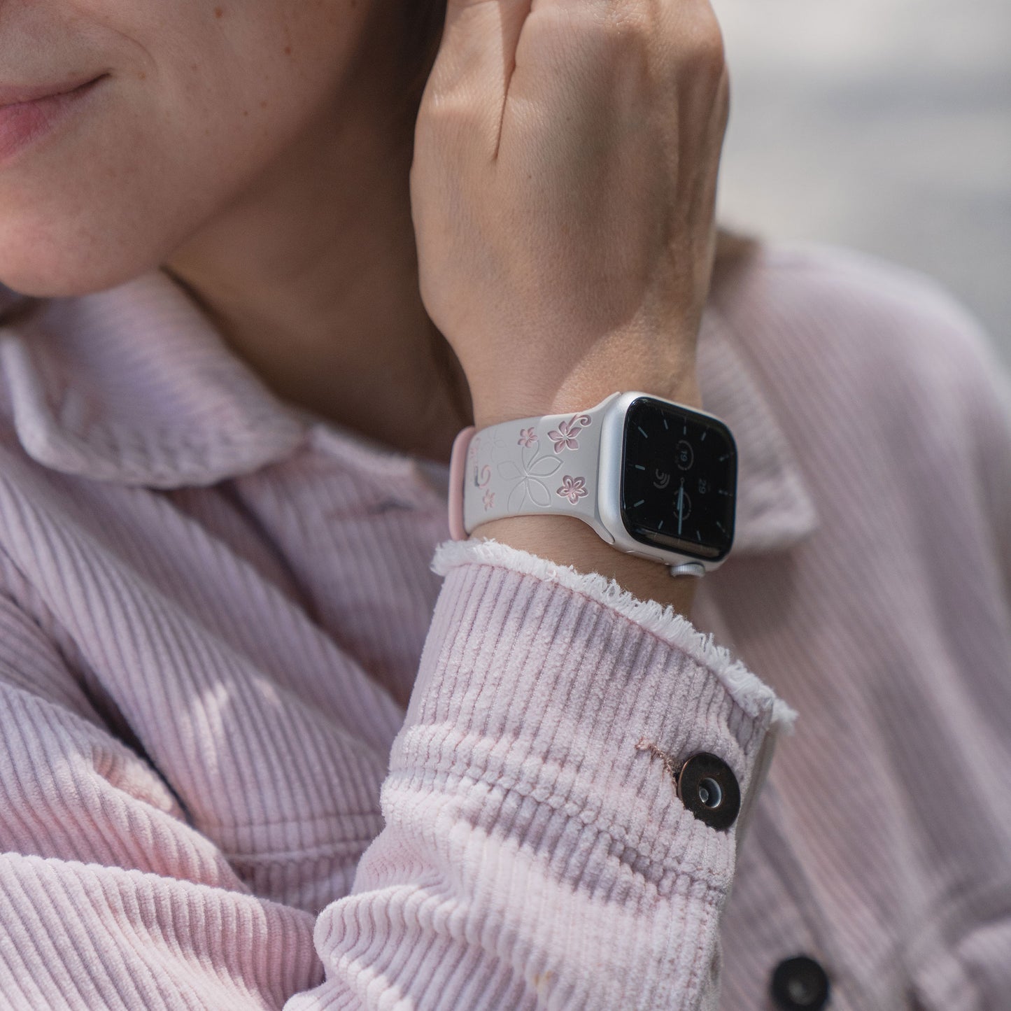 Person trägt eine hellrosa Cordjacke und ein arktisband Apple Watch Silikonarmband "Bloom" von arktisband am Handgelenk.