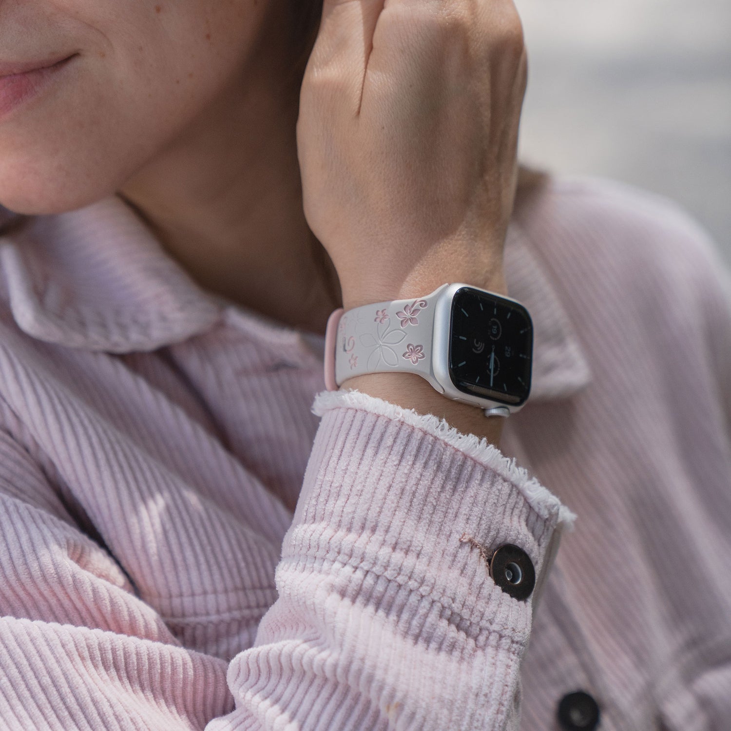 Person trägt eine hellrosa Cordjacke und ein arktisband Apple Watch Silikonarmband "Bloom" von arktisband am Handgelenk.