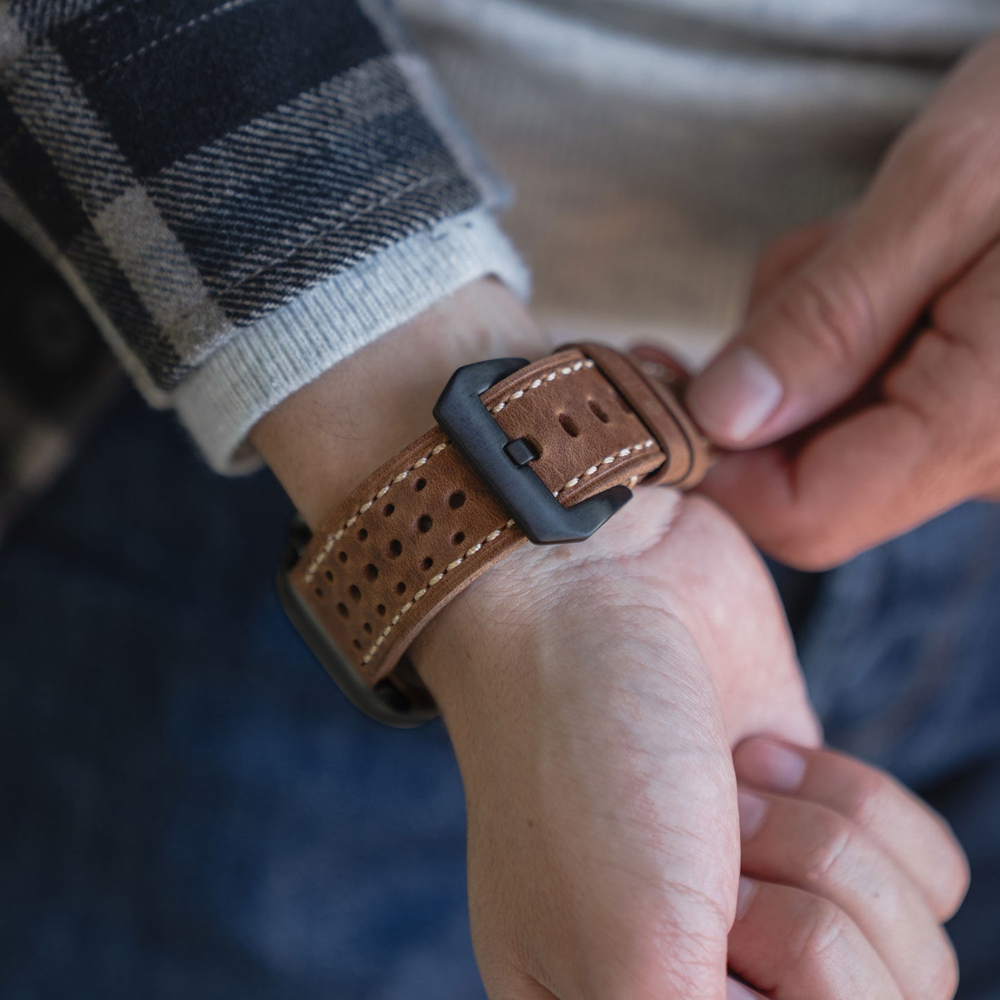 Eine Person befestigt das arktisband Apple Watch Lederarmband "Toronto" mit weißen Nähten an ihrem Handgelenk und unterstreicht damit die arktisband Qualität Echtleder und klassisches Vintage-Design.