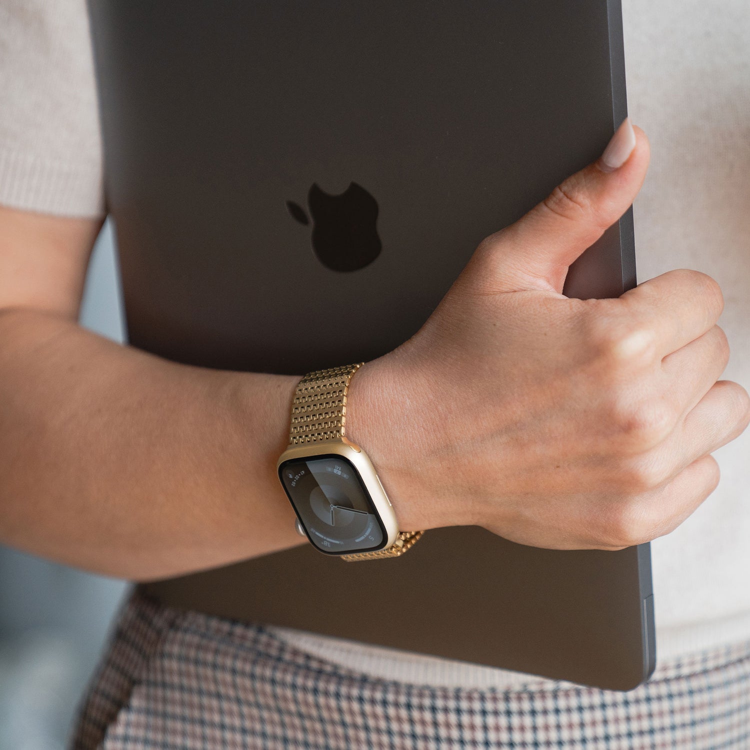 Person hält ein schwarzes MacBook und trägt ein arktisband Apple Watch Edelstahlarmband „Aurora“ von arktisband mit einem eleganten Magnetverschluss am Handgelenk.