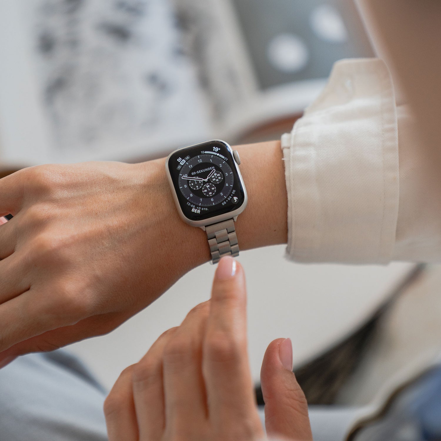 Man tippt auf das arktisband Apple Watch Gliederarmband „Arctica“ – Slim mit rundem, schwarzem Display. Das elegante Edelstahlarmband von arktisband zeigt die Uhrzeit und weitere Details auf dem Zifferblatt an.