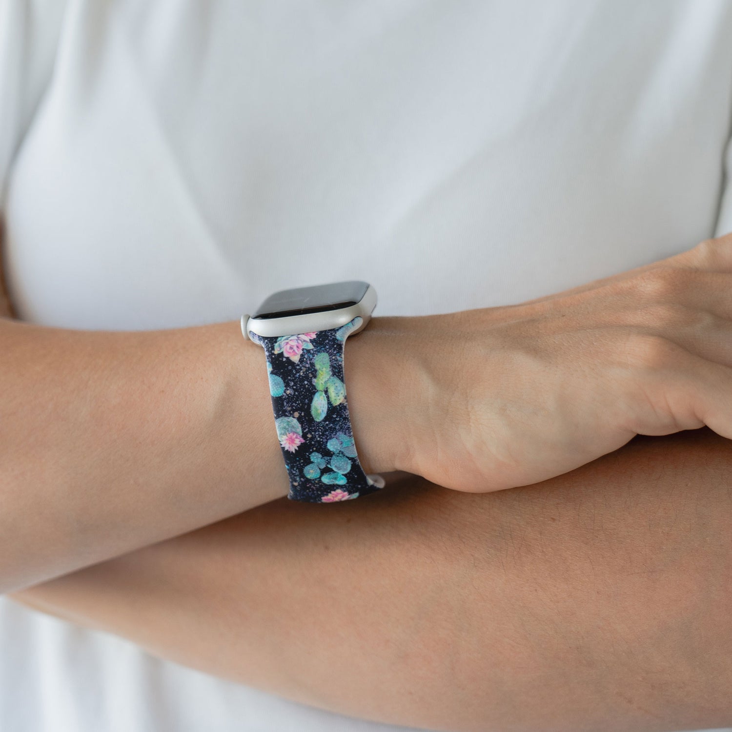 Eine Person trägt eine arktisband EDITION für Apple Watch, ein dunkles, floral gemustertes Armband von arktisband, an ihrem Handgelenk.