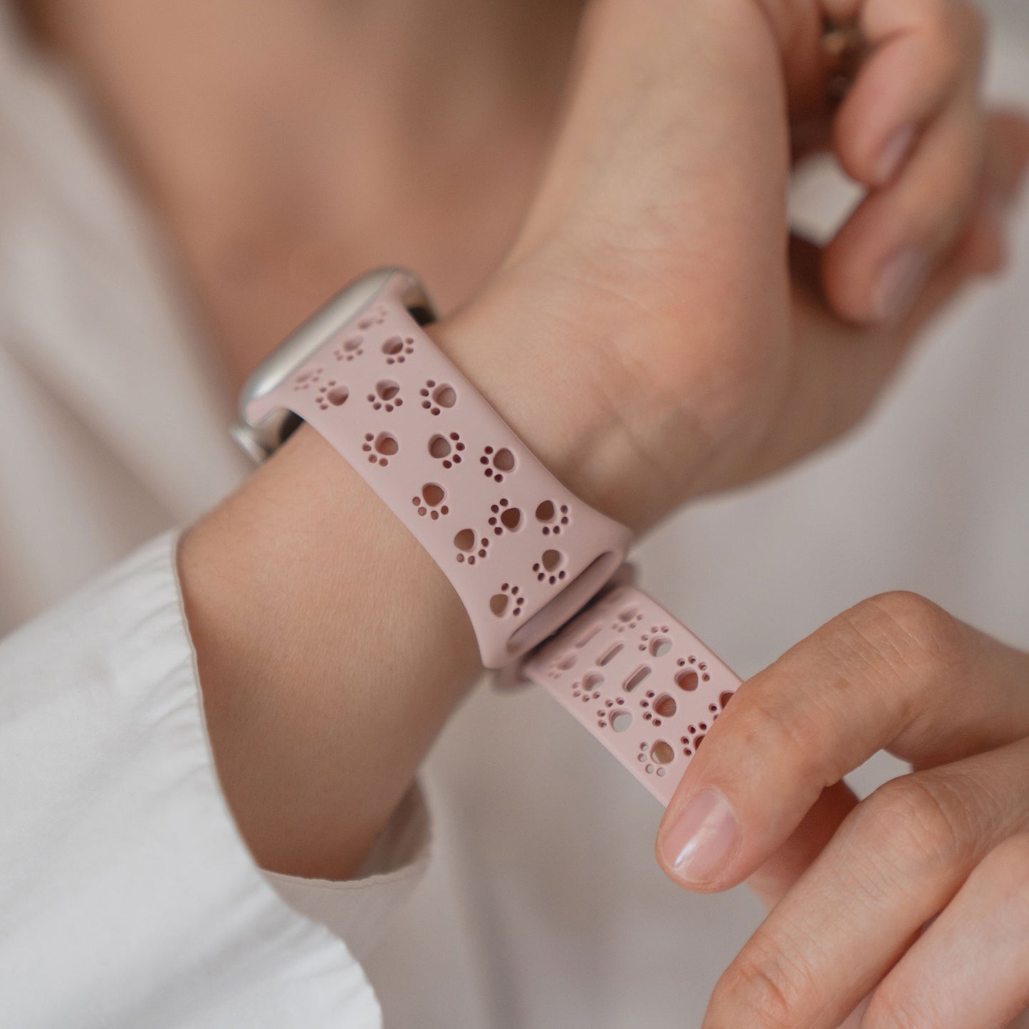 Jemand befestigt ein arktisband Apple Watch Silikonarmband "Paw" mit verspielten Pfotenabdrücken an seinem Handgelenk und setzt damit einen stilvollen und lustigen Akzent auf seine Apple Watch.