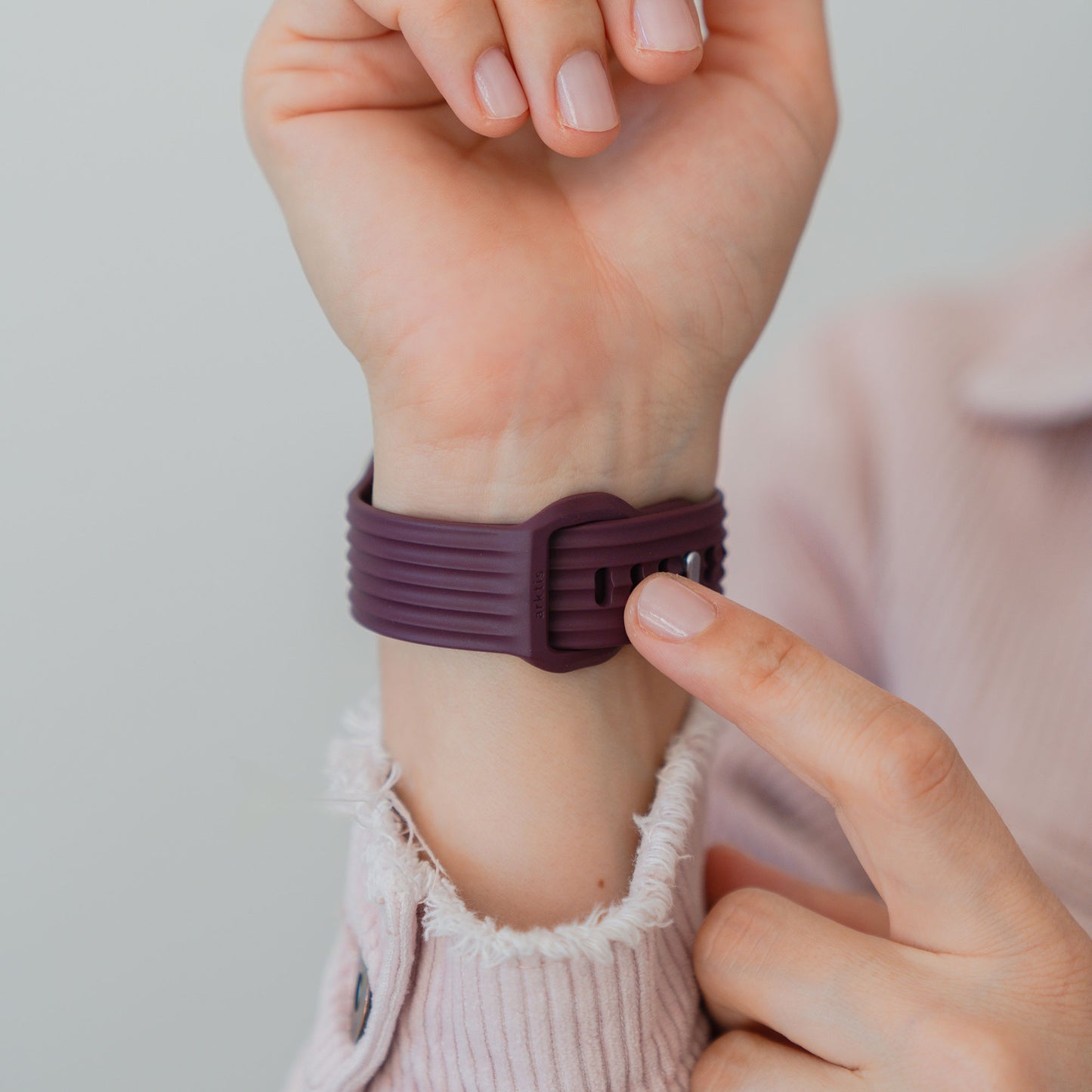 Jemand befestigt ein arktisband Apple Watch Armband "Skandi" in lila Fluorelastomer von arktisband an seinem Handgelenk.