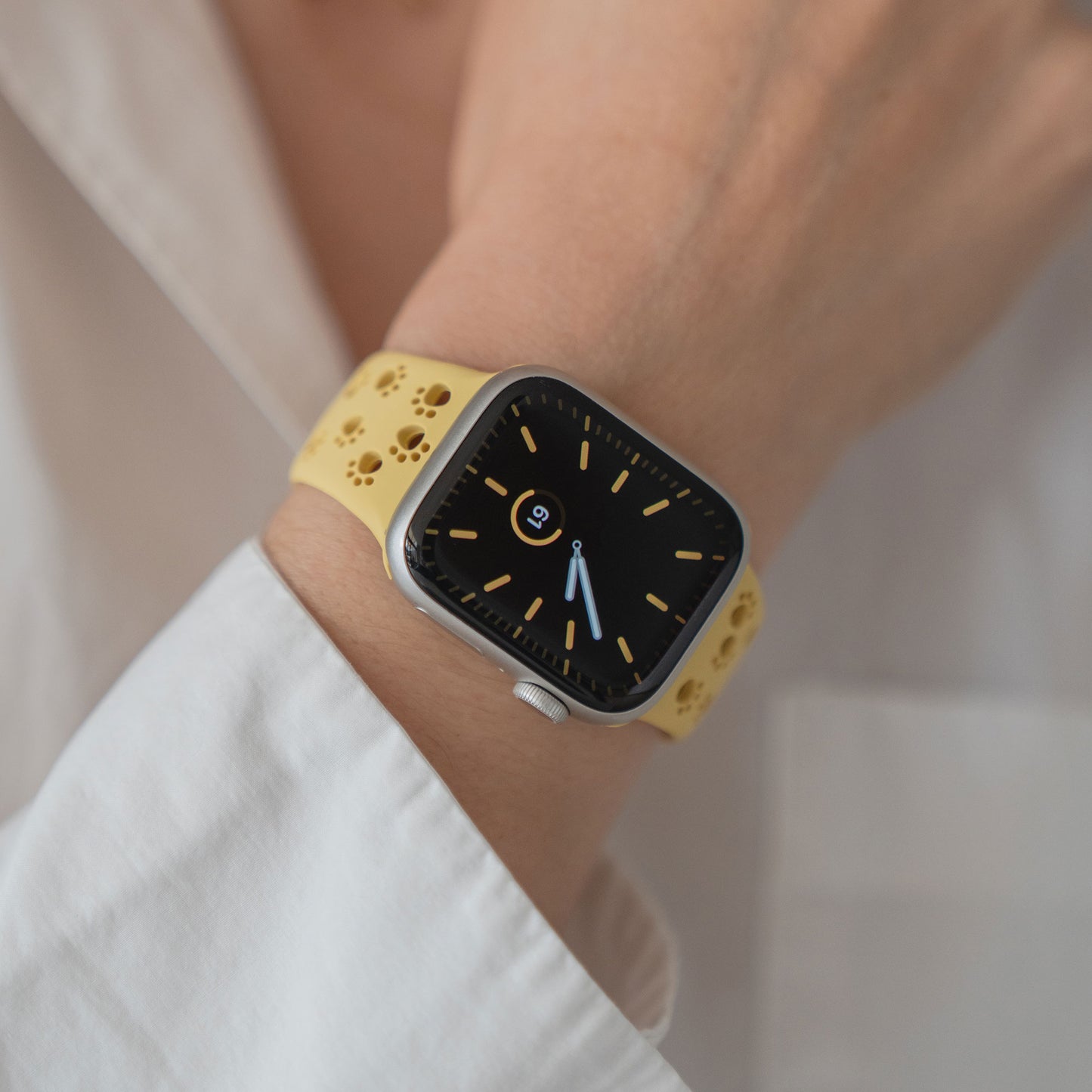 Eine Person, die ein Arktisband Apple Watch Silikonarmband "Paw" in Gelb mit schwarzem Zifferblatt trägt, bekleidet mit einem weißen Hemd.