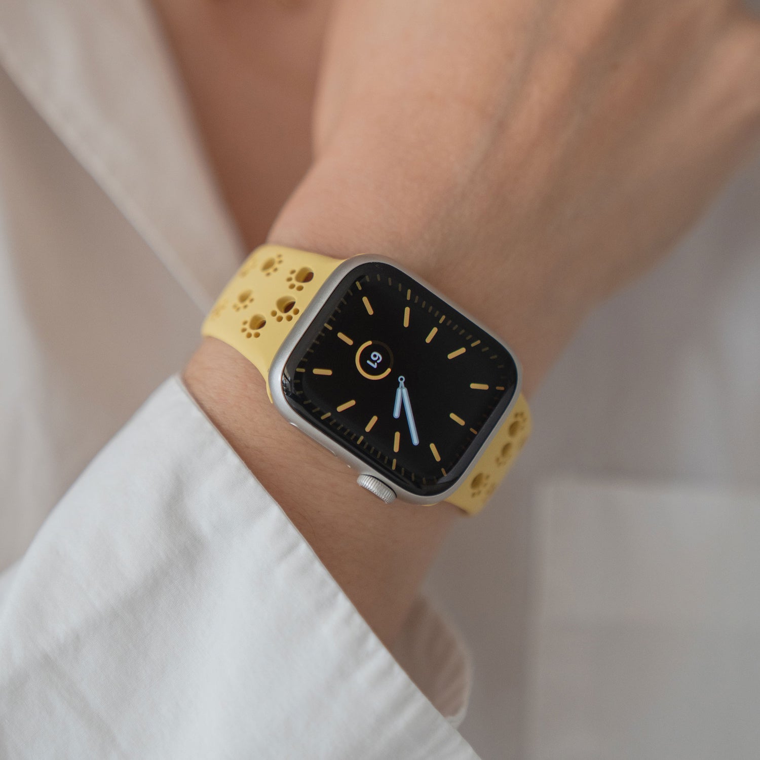 Eine Person, die ein Arktisband Apple Watch Silikonarmband "Paw" in Gelb mit schwarzem Zifferblatt trägt, bekleidet mit einem weißen Hemd.