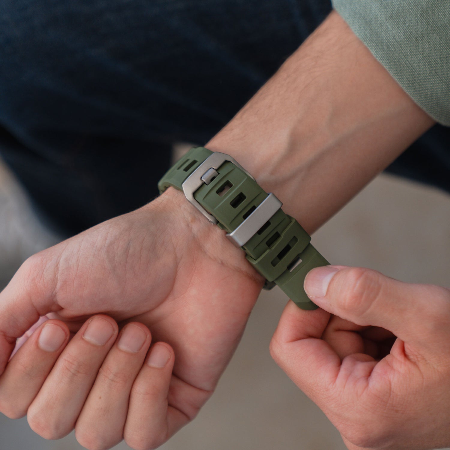 Nahaufnahme einer Person, die das arktisband Apple Watch Armband "Flux" mit einer Edelstahl-Schließe um ihr Handgelenk befestigt.