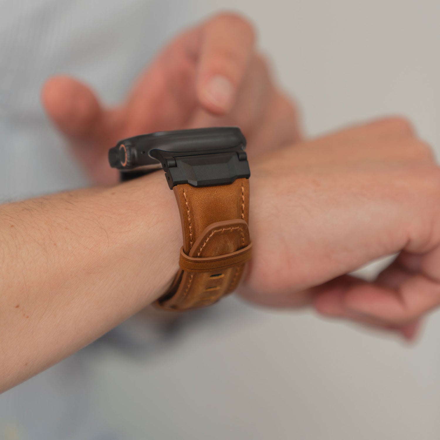 Jemand befestigt das arktisband Apple Watch Ultra Lederarmband "Delta" in braun von arktisband an seinem Handgelenk.