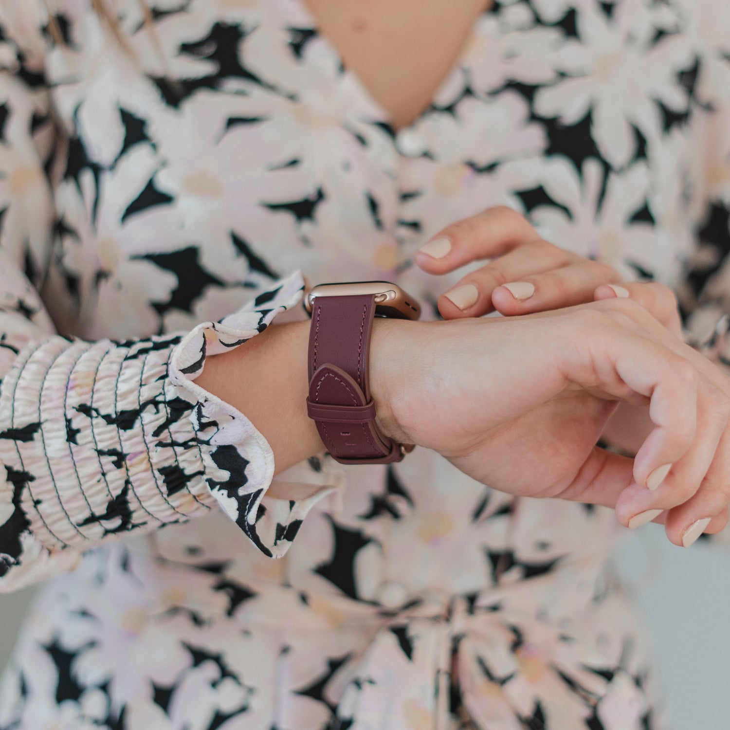 Eine Frau in einem geblümten Kleid passt ihr arktisband Apple Watch Lederarmband "Premium" von arktisband an ihr Handgelenk an.