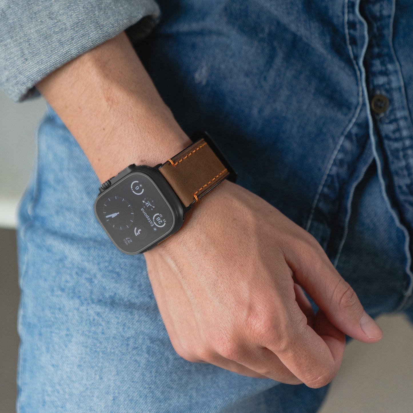 Jemand trägt eine arktisband Apple Watch Ultra mit dem PALERMO GRANDE Lederarmband und Jeanskleidung.