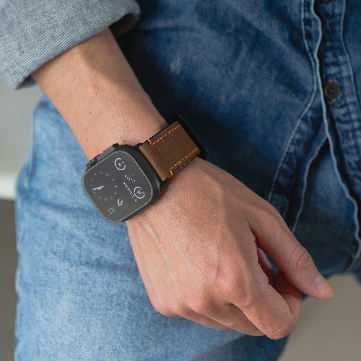 Jemand trägt eine arktisband Apple Watch Ultra mit dem PALERMO GRANDE Lederarmband und Jeanskleidung.
