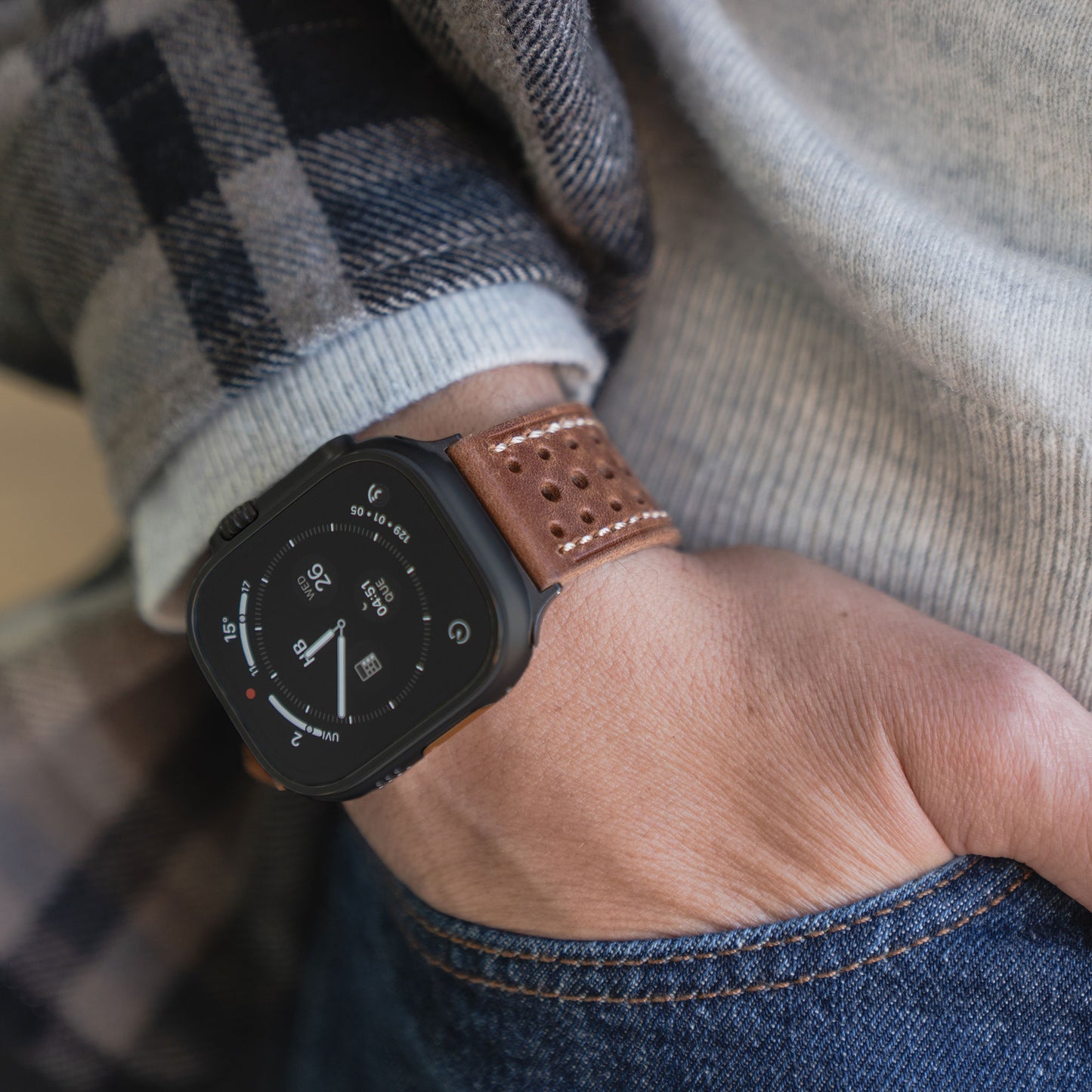 Nahaufnahme einer Person, die ein Arktisband Apple Watch Lederarmband "Toronto" im braunen Vintage-Design trägt, die Hand lässig in die Jeanstasche gesteckt.