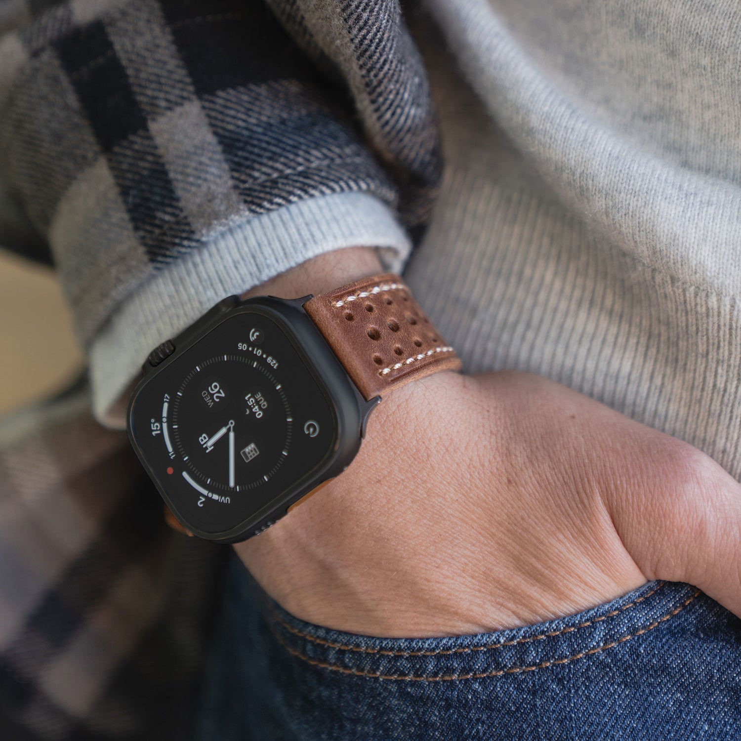 Nahaufnahme einer Person, die ein Arktisband Apple Watch Lederarmband "Toronto" im braunen Vintage-Design trägt, die Hand lässig in die Jeanstasche gesteckt.