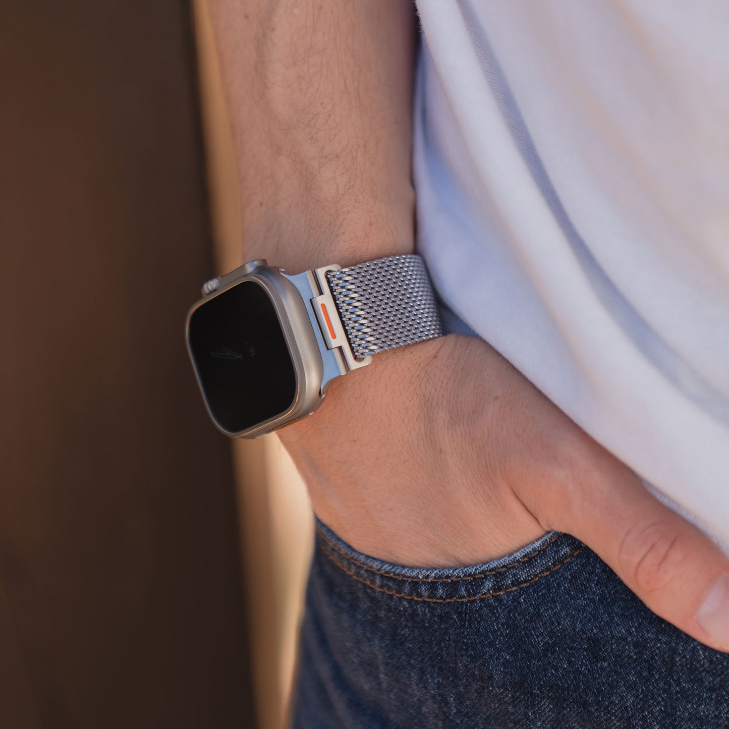 Eine Person mit einem Arktisband Apple Watch Milanaise Armband "Bold SE" Special Edition in Silber, Hand in der Tasche, bekleidet mit Jeans und weißem Hemd.