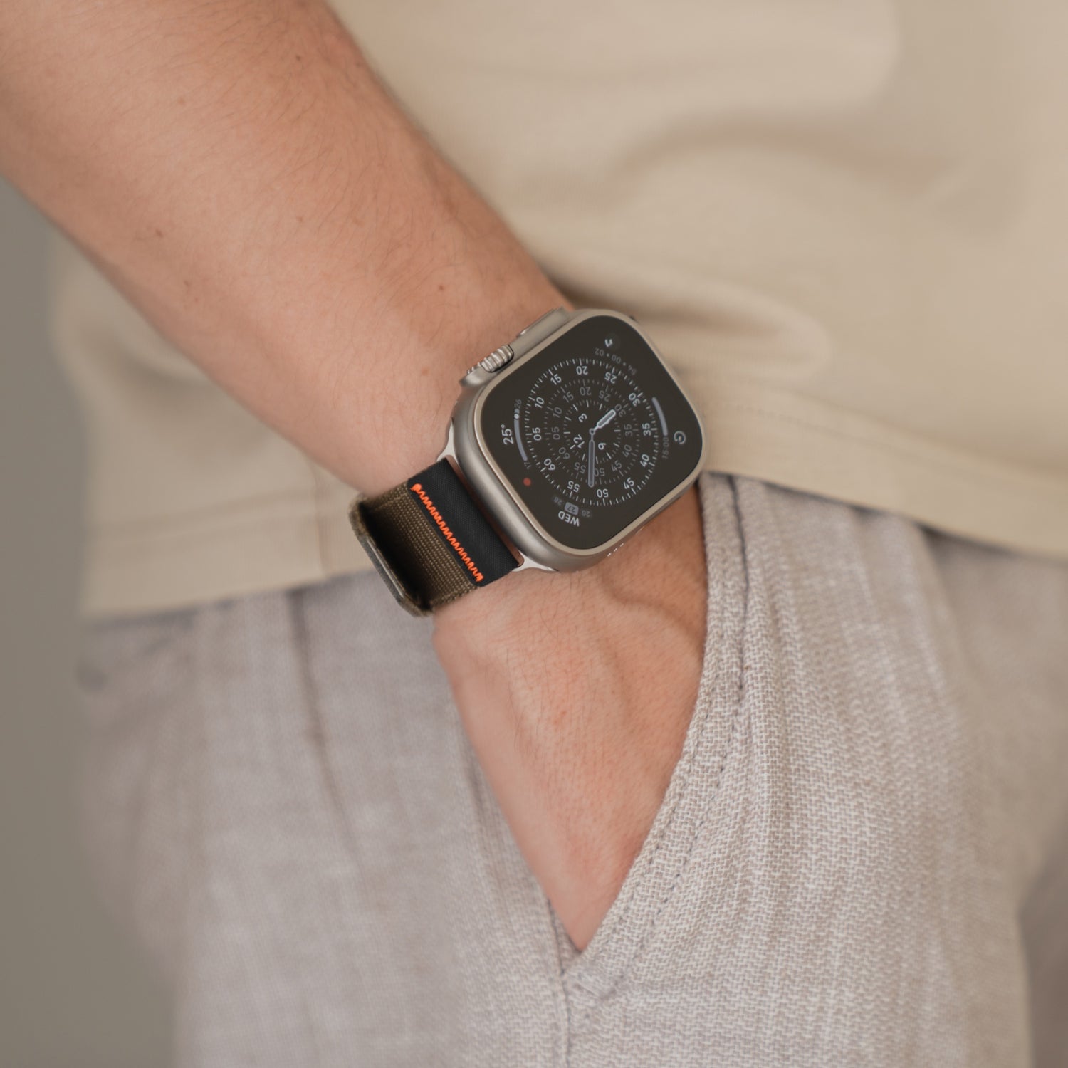 Person trägt das arktisband Apple Watch Armband "Terra" von arktisband, ein 24 mm extrabreites Nylonband in Schwarz, gepaart mit heller Kleidung und Hand in der Tasche.