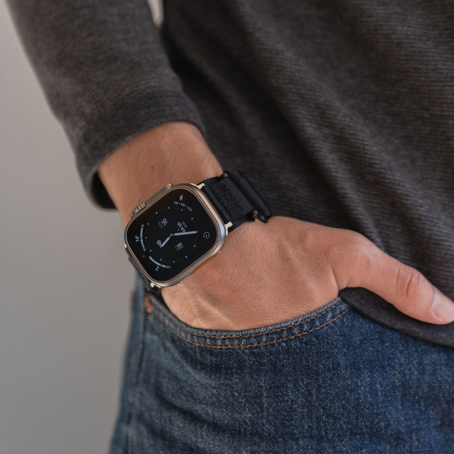 Eine Person, die das arktisband Apple Watch Outdoor Armband "Forge" von arktisband mit einem schwarzen Armband und einem dunklen Pullover trägt, die Hand in der Tasche einer blauen Jeans.