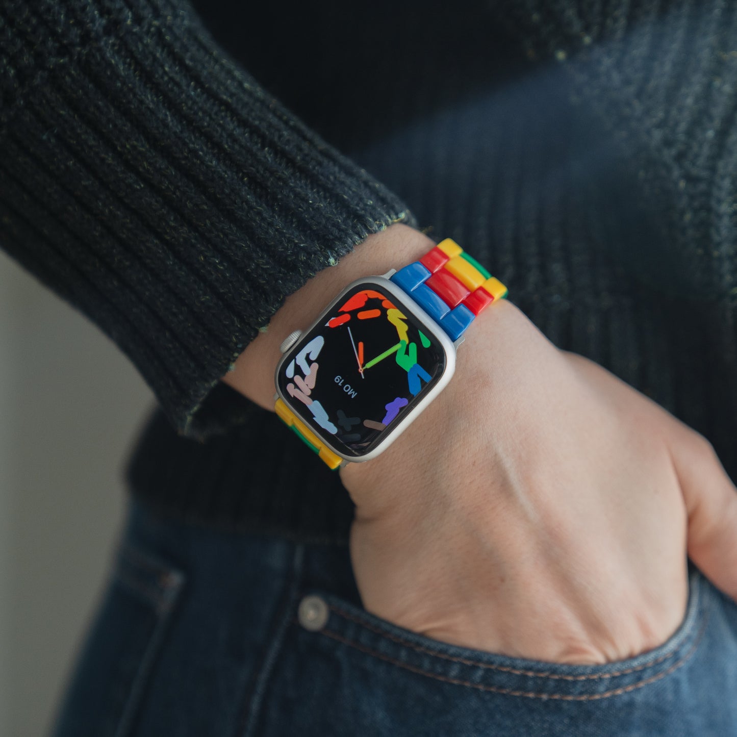 Eine Person trägt das arktisband Apple Watch "Pixel Band" mit einem Regenbogenarmband und einem abstrakten Design auf dem Acrylglas-Bildschirm von arktisband.