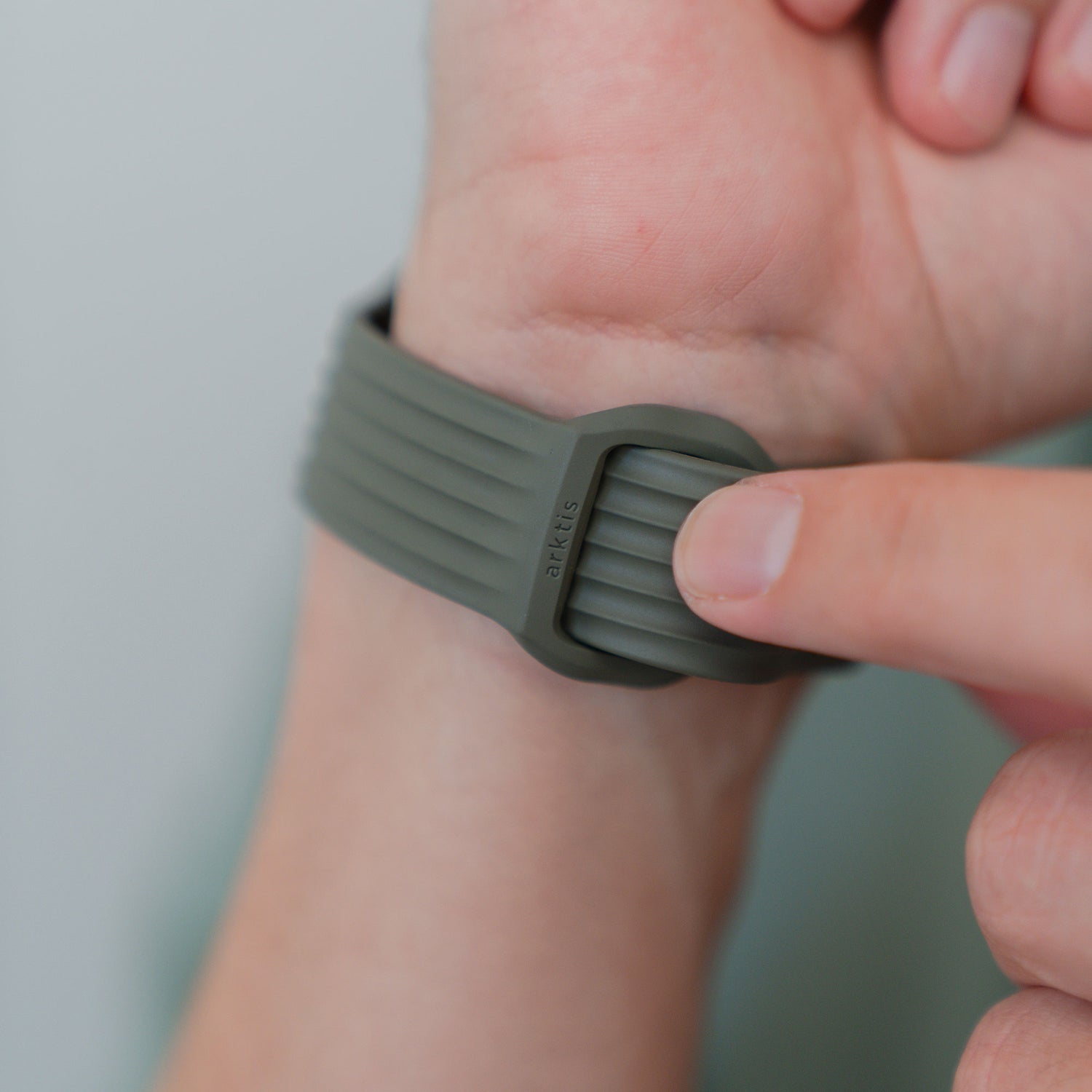 Einstellen des Verschlusses eines grauen, gerippten arktisband Apple Watch Armbands "Skandi" von arktisband, gefertigt aus haltbarem Fluorelastomer für einen minimalistischen skandinavischen Look.