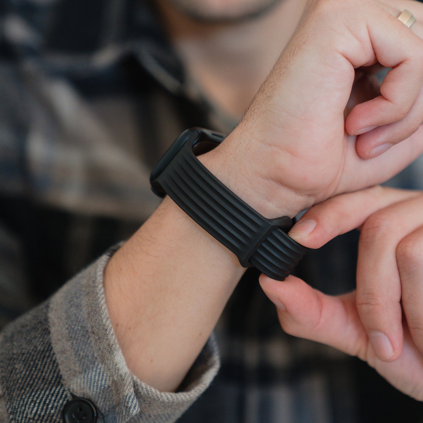 Eine Person in einem karierten Hemd stellt ihr arktisband Apple Watch Armband "Skandi" von arktisband ein und hebt dessen schlankes Design hervor.